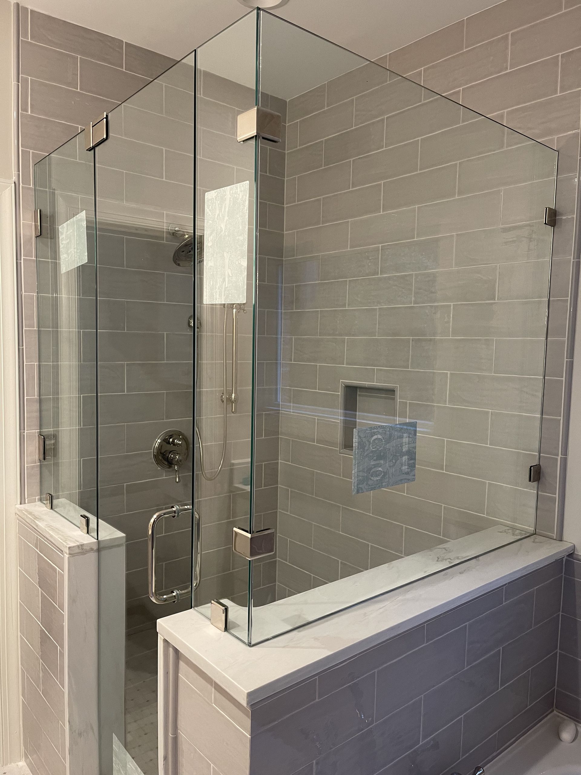 A bathroom with a glass shower door and a bathtub.