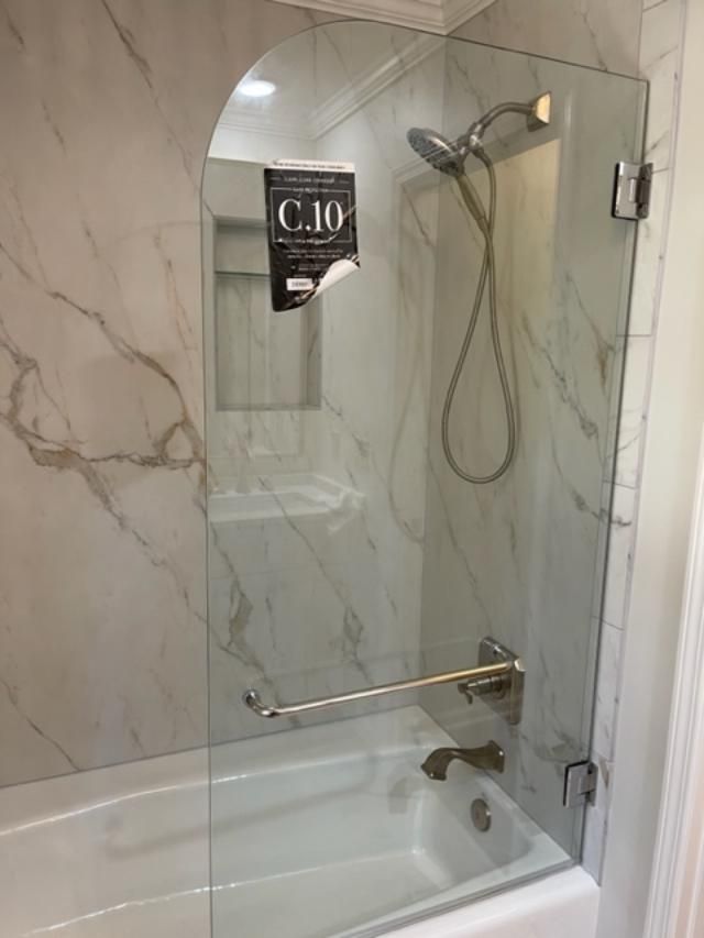 A bathroom with a bathtub and a shower with a glass door.