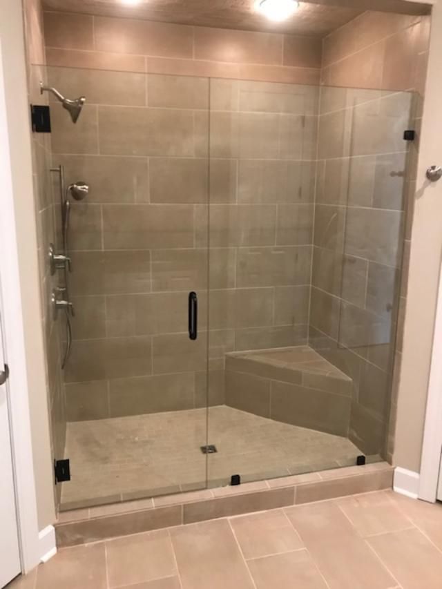 A bathroom with a walk in shower with a glass door.