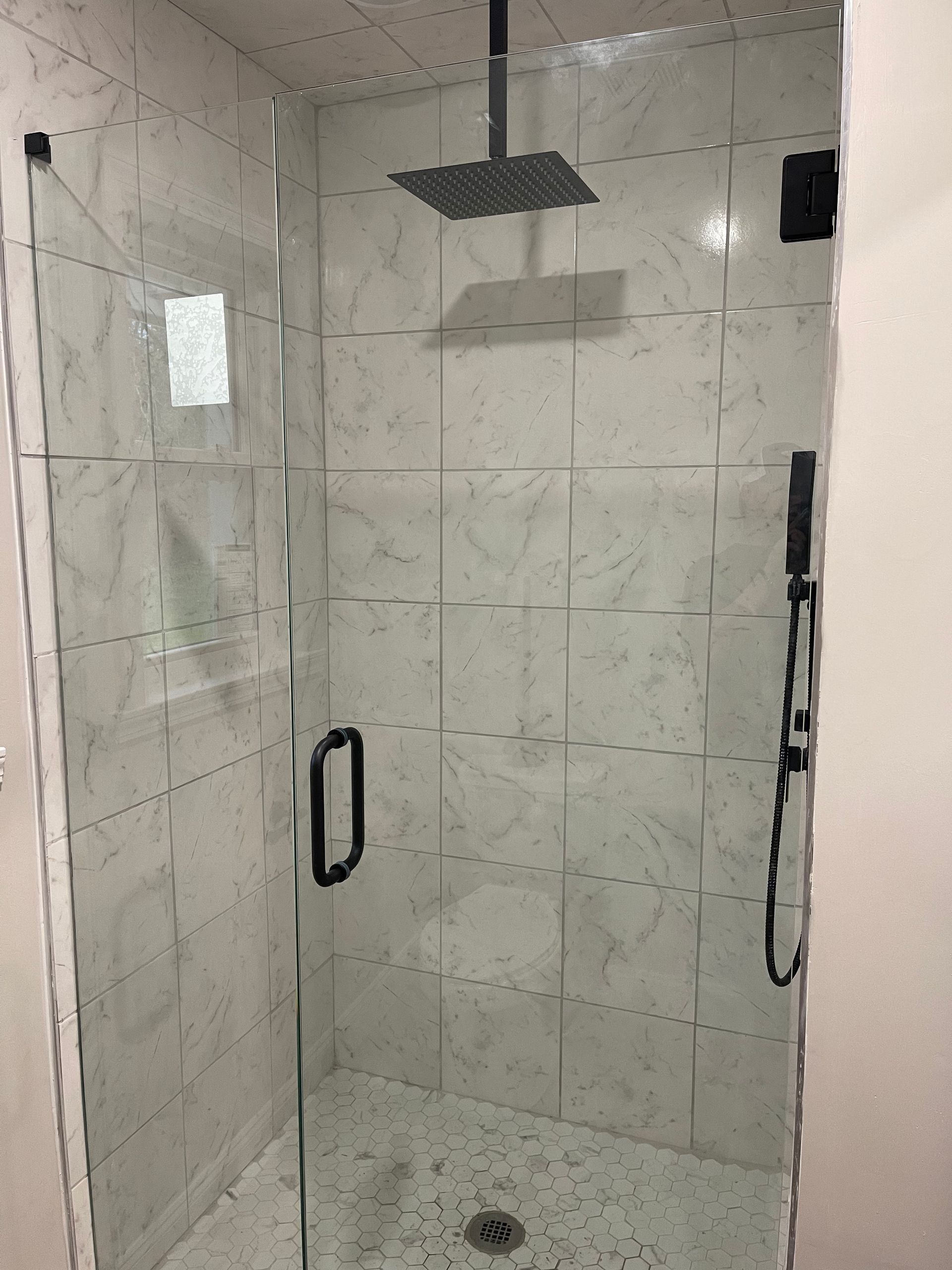 A shower with a glass door and a shower head hanging from the ceiling.