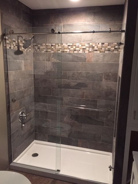 A bathroom with a walk in shower with a glass door