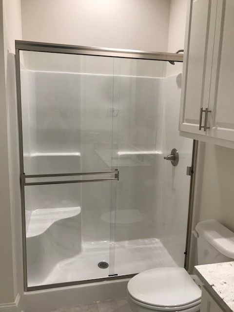 A bathroom with a sliding glass shower door and a toilet.