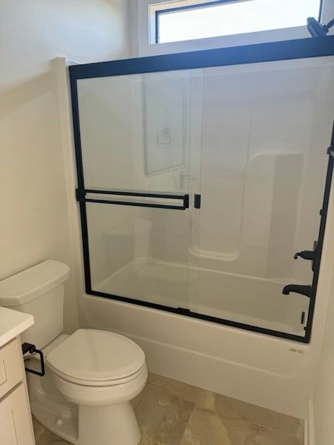 A bathroom with a toilet a bathtub and a sliding glass shower door