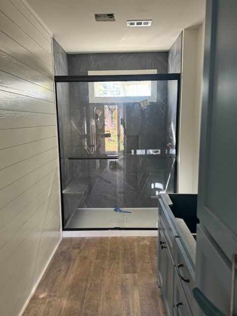 A bathroom with a sliding glass shower door and a sink.