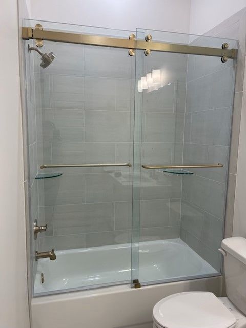 A bathroom with a bathtub , toilet and shower stall with sliding glass doors.