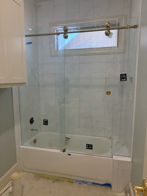 A bathroom with a bathtub and a sliding glass shower door.