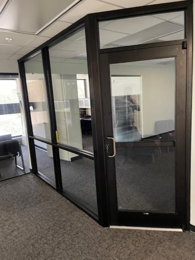 There is a door in the middle of a room with glass walls.