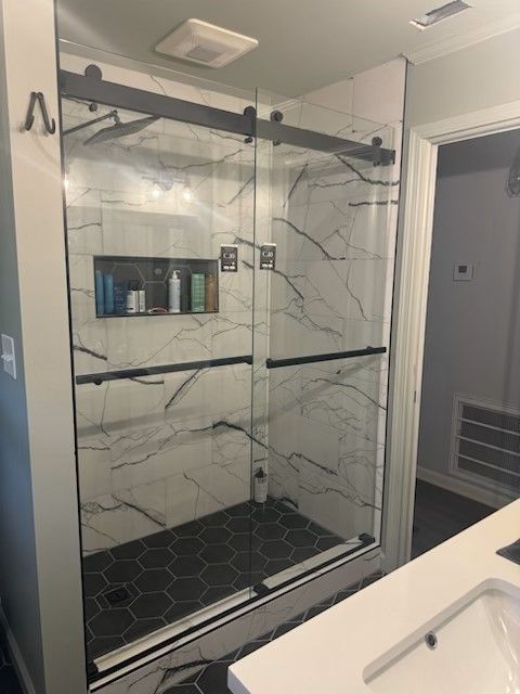 A bathroom with a sliding glass shower door and a sink