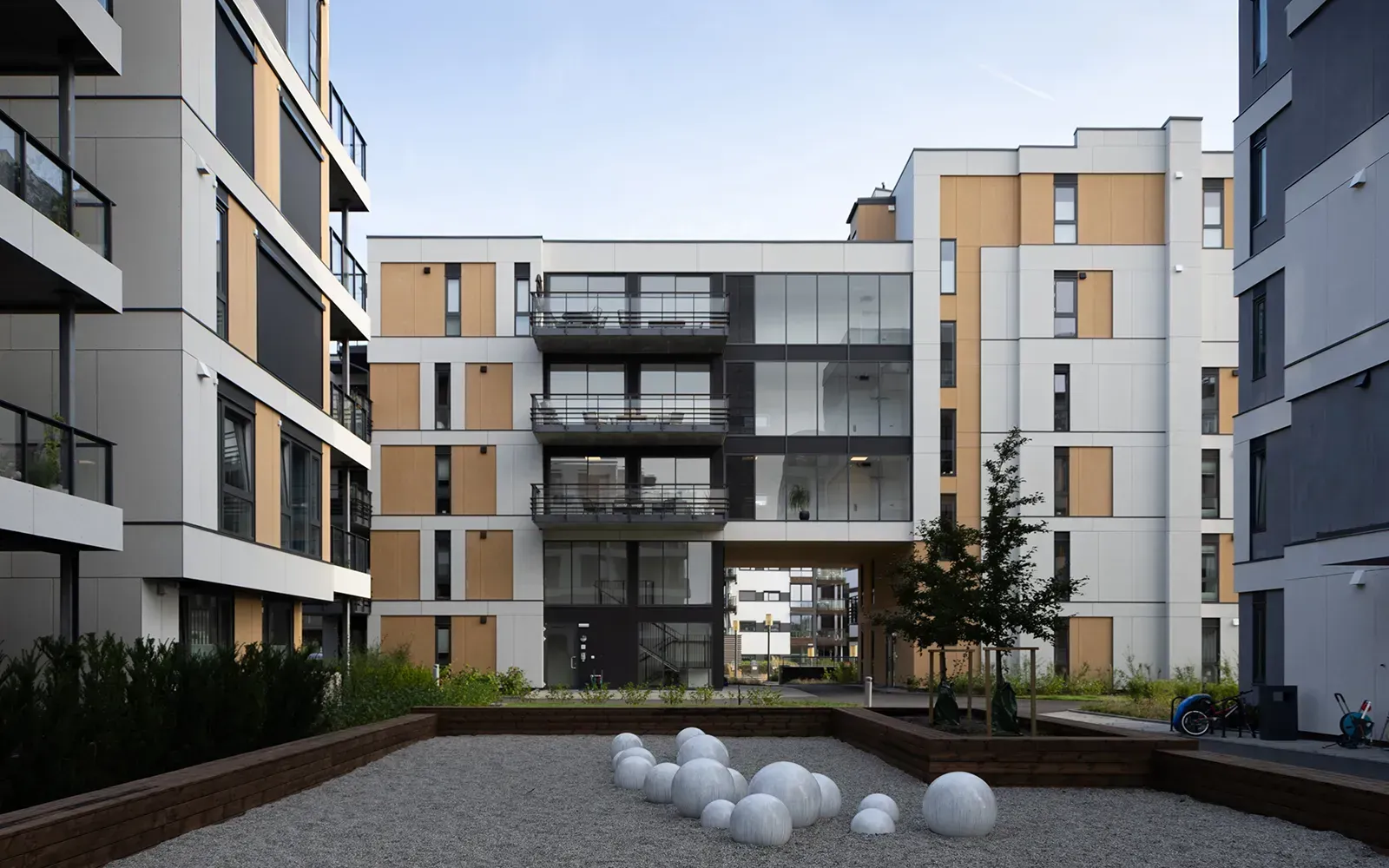 Boligblokk ved Nordre Jarlsberg Brygge i Sande med hvite, mørke og gule plater, felles lekeplass og skulpturer