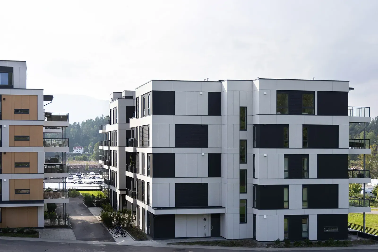 Boligblokker i Bryggeparken med fasade i grå, gule og hvite Equitone-plater og utsyn mot marina og grøntområder