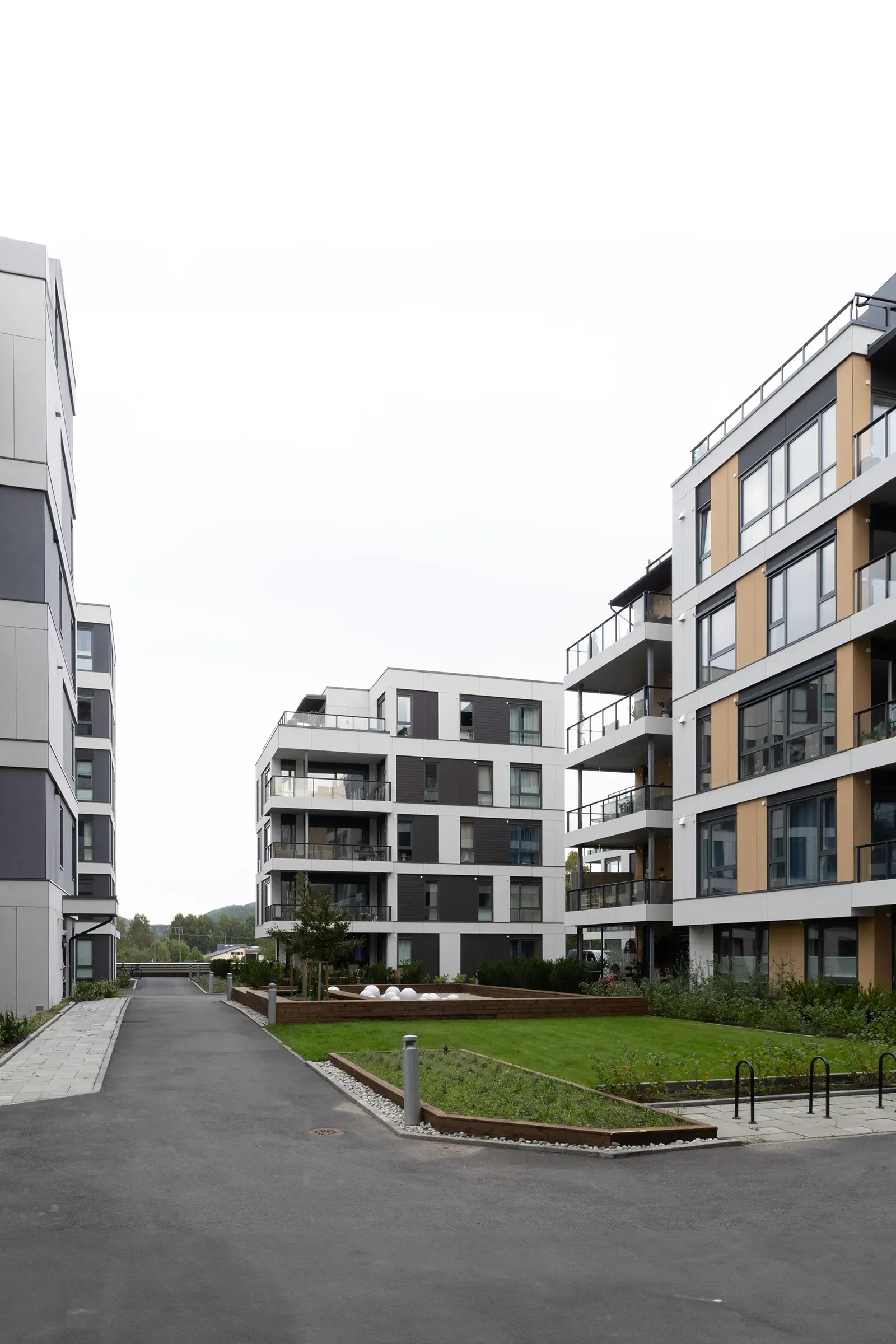 Boligblokk i Bryggeparken med store vinduer, fasade i gule, hvite og grå Equitone-plater og grønt uterom