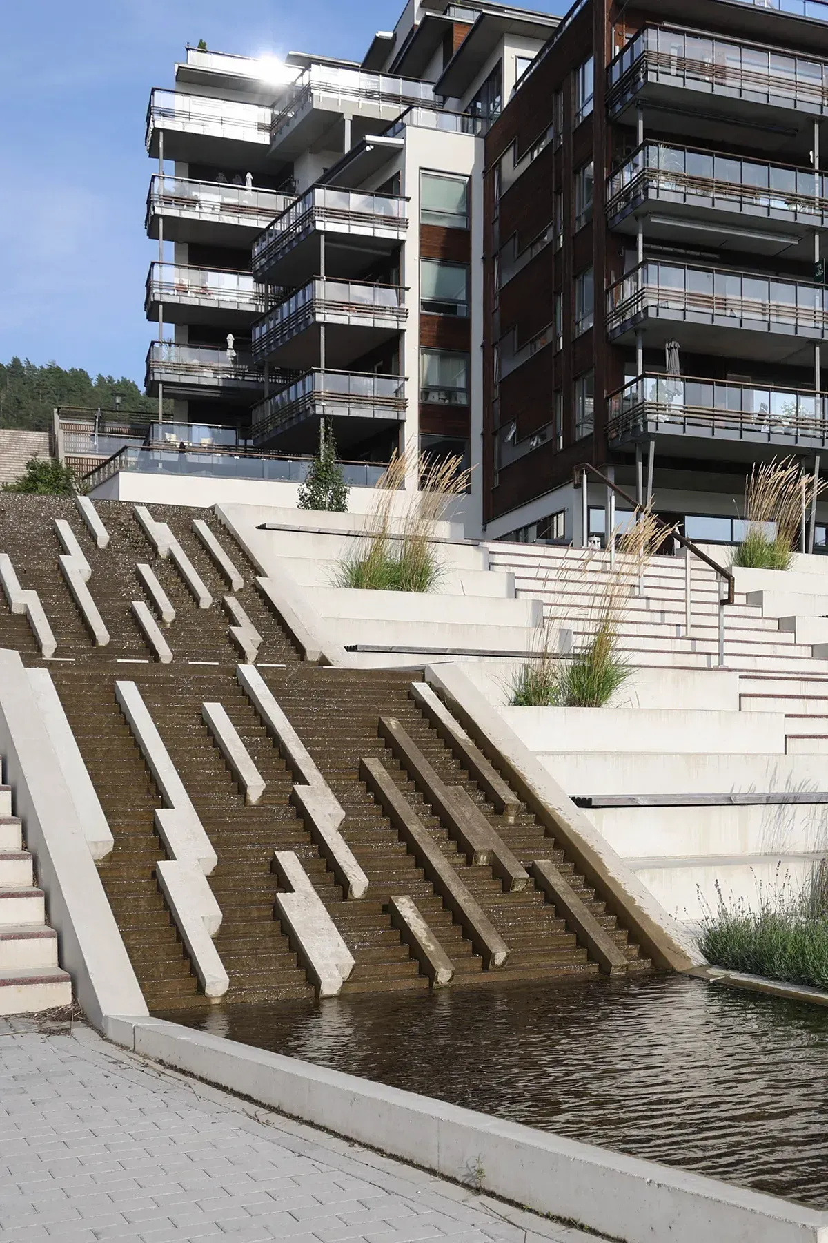 Detalj av vanntrapp med geometriske betongelementer der vannet renner nedover som et arkitektonisk blikkfang.