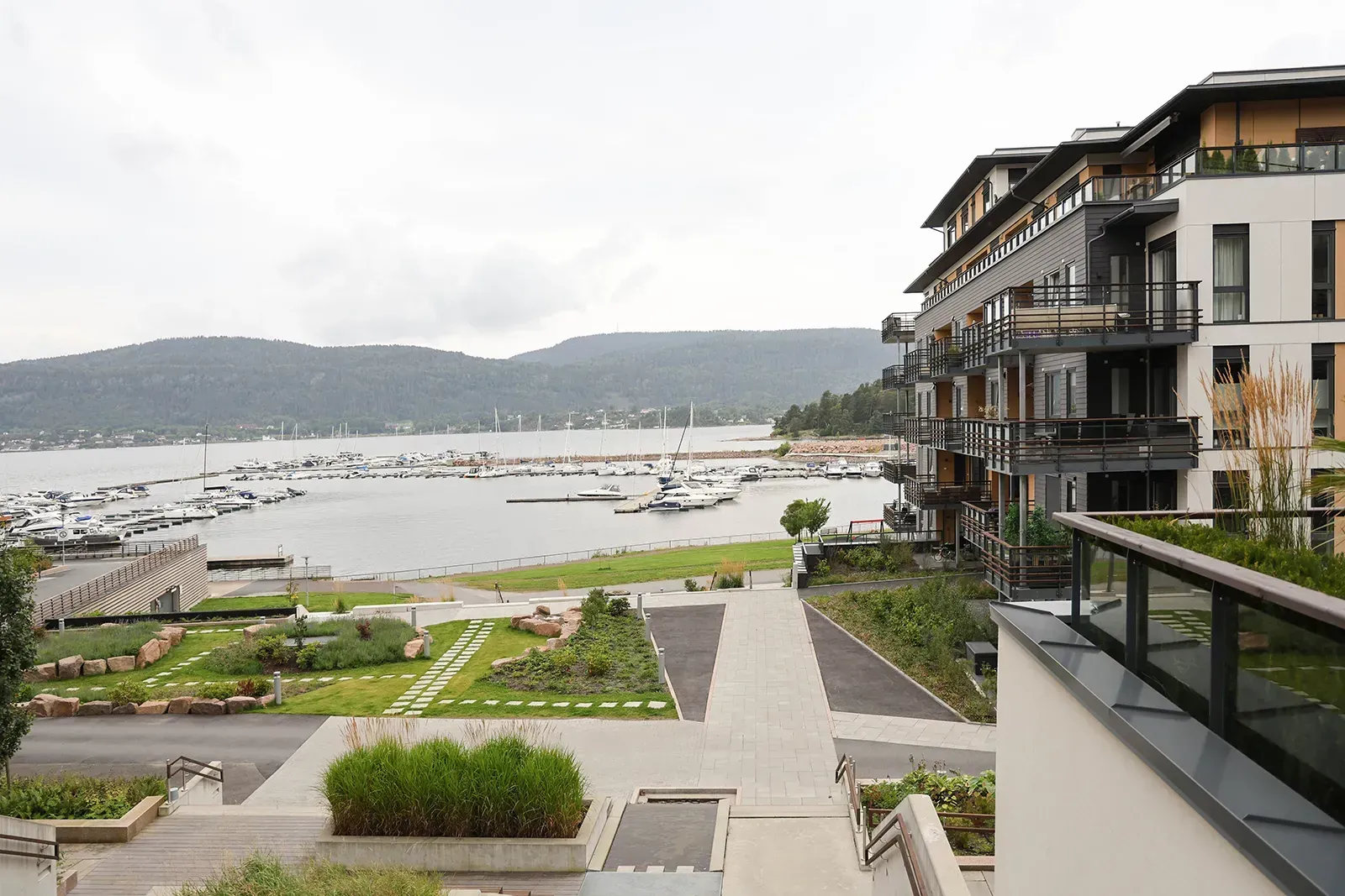 Utsikt fra Torgtrappen mot marinaen og fjorden, med grønne oppholdsarealer og stensatte ganglinjer.