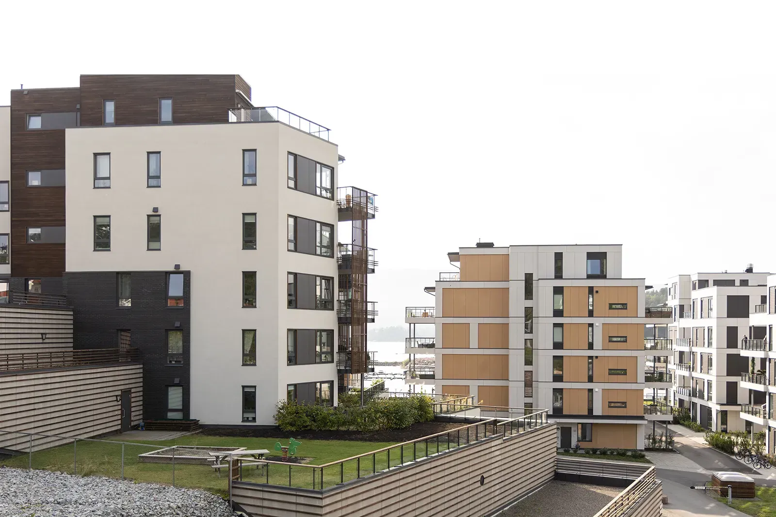 Boligblokker med varierte fasader, balkonger og felles uteområder med grøntanlegg.
