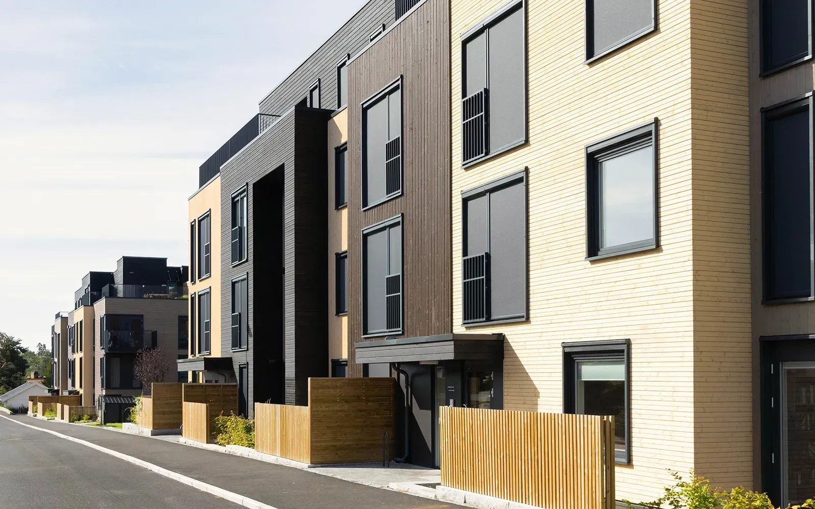 Fasadeutsnitt i Østensjøporten med beige, brun og svart trekledning, store vinduer og moderne inngangsparti mot Bogerudveien