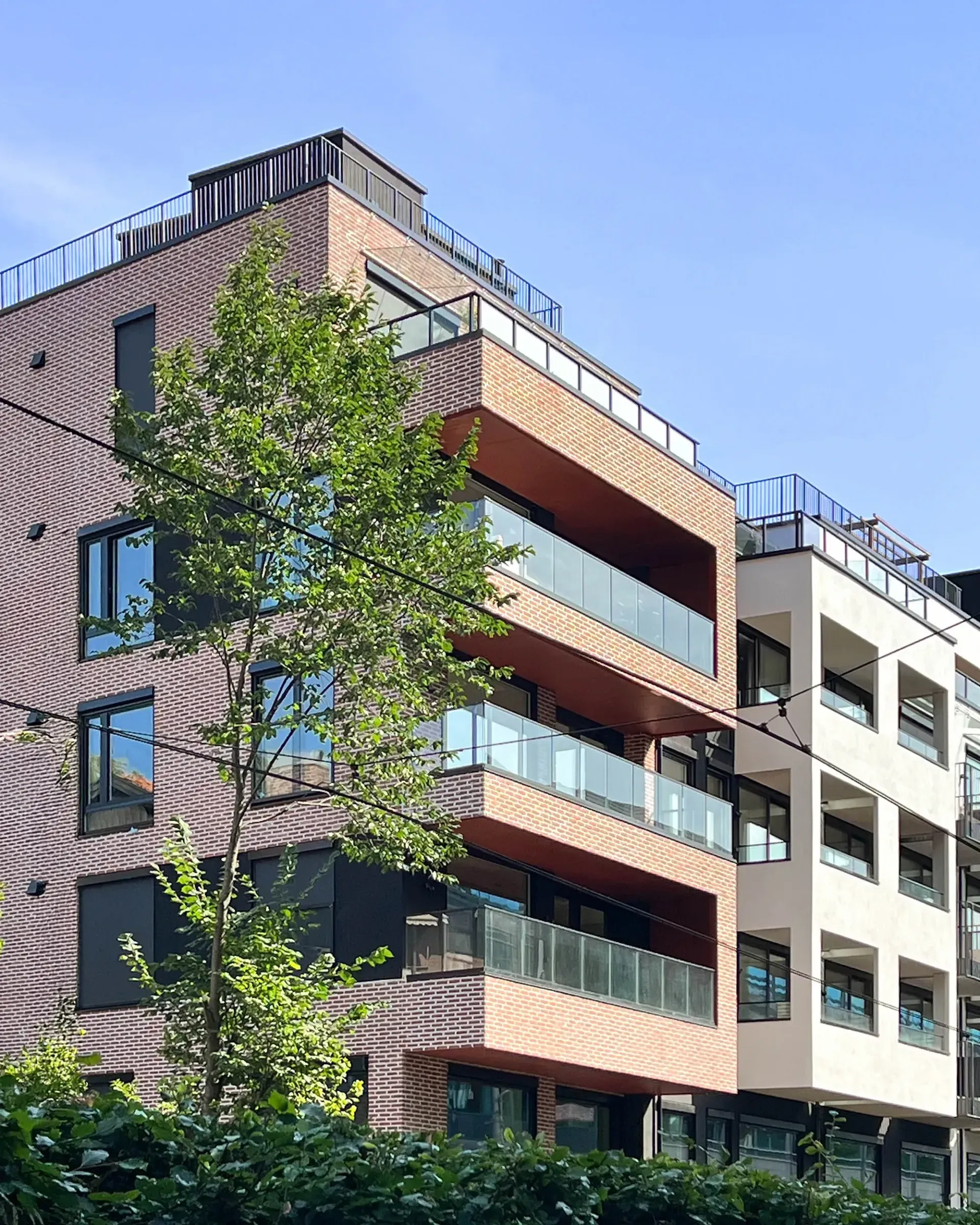 Gateperspektiv av boligbebyggelse på Skøyen, Oslo, med teglfasade, mørke felter og balkonger vendt mot gangvei