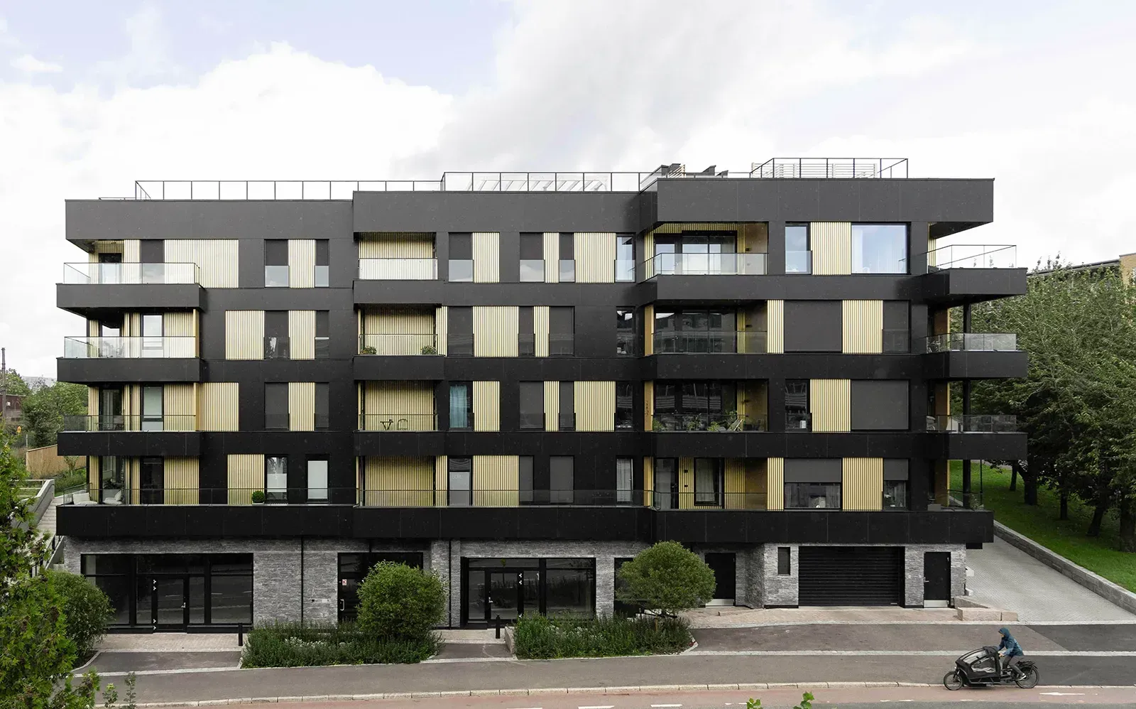 Gatefasade på Tøyentaket i Ensjøveien med svarte og gule fasadeplater, store vinduer og inntrukne balkonger med glassrekkverk