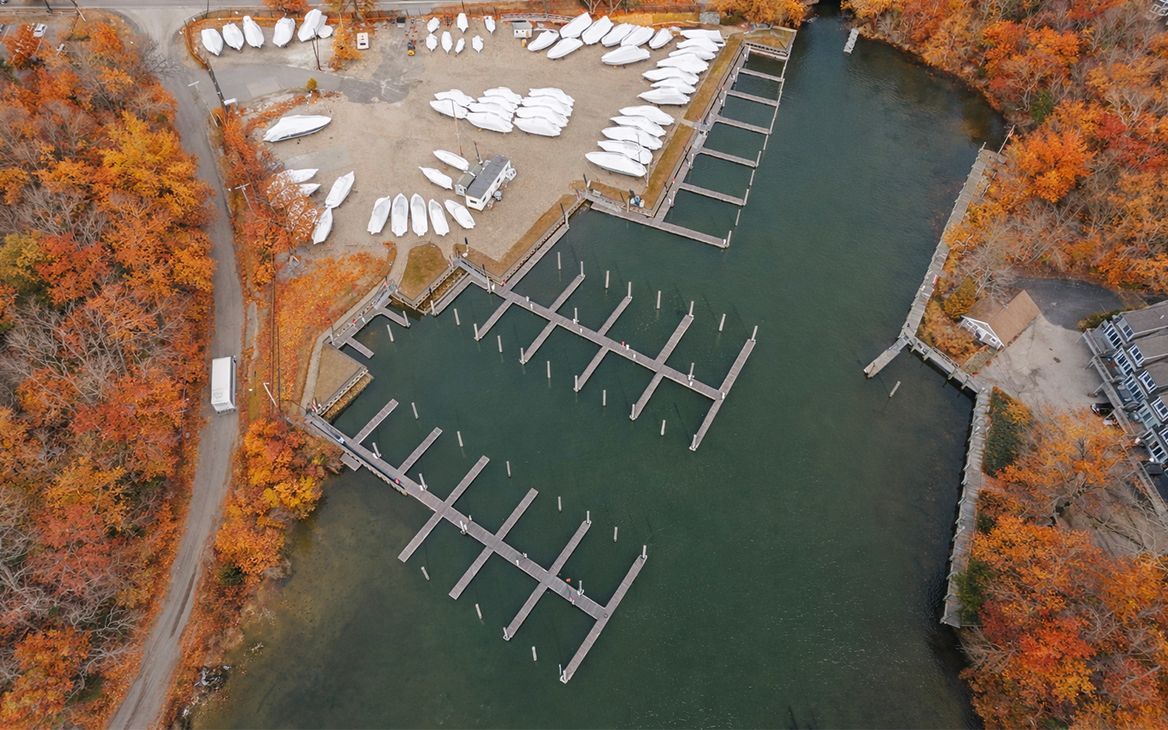 Aerial view of a marina with docks, boats, and surrounding autumn foliage.