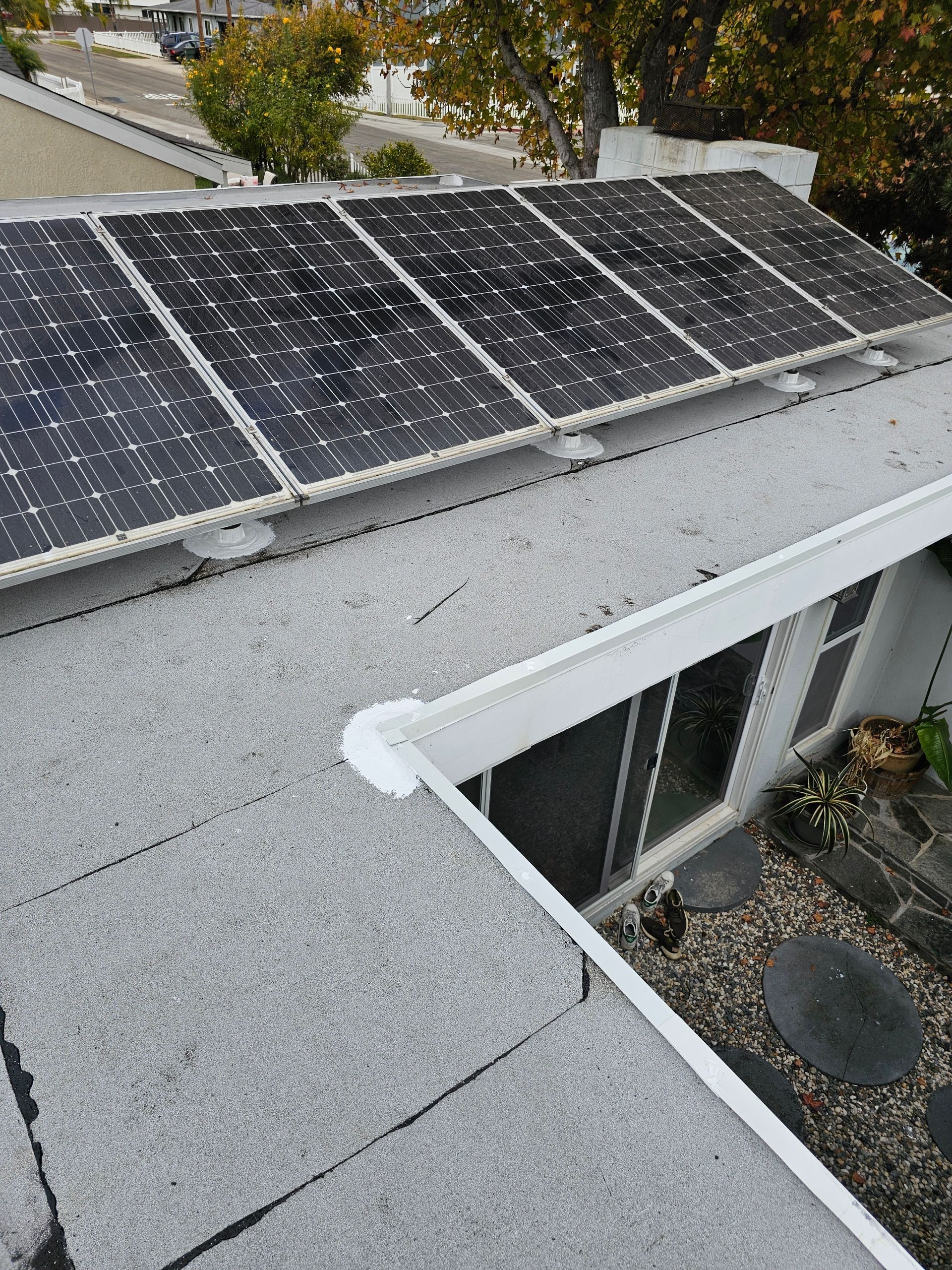 Solar panels on a flat roof next to white gutters. The sky is visible in the background.