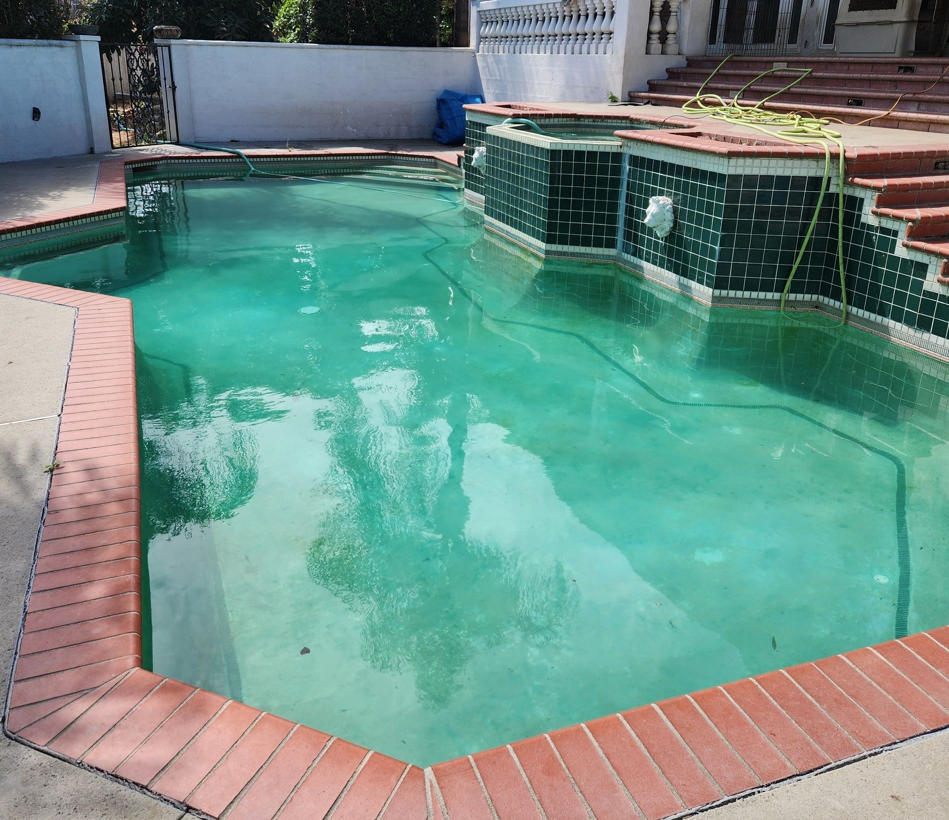 There is a large swimming pool in the backyard of a house.