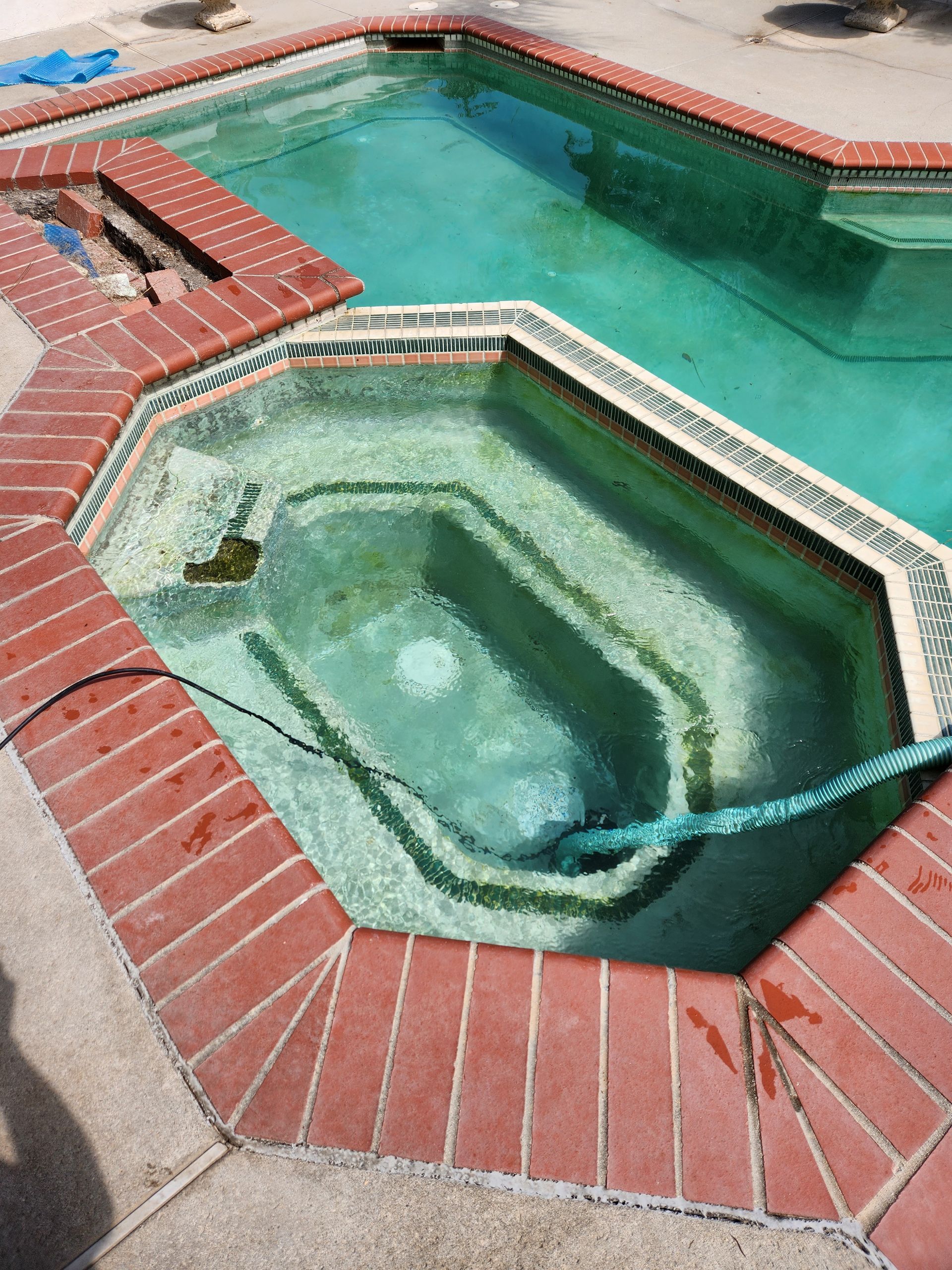 A swimming pool with a hose attached to the side of it.
