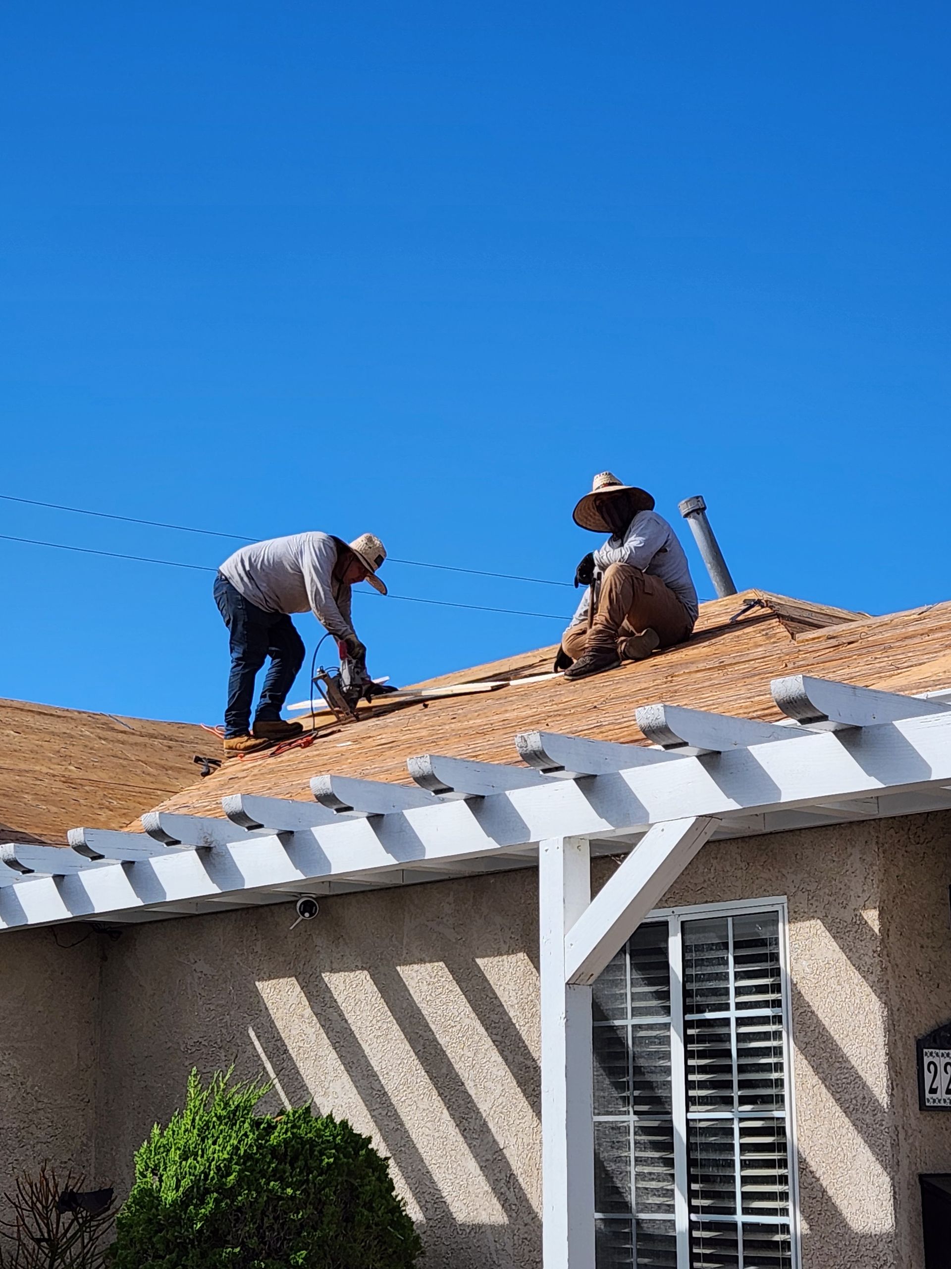 Two men are working on the roof of a house.