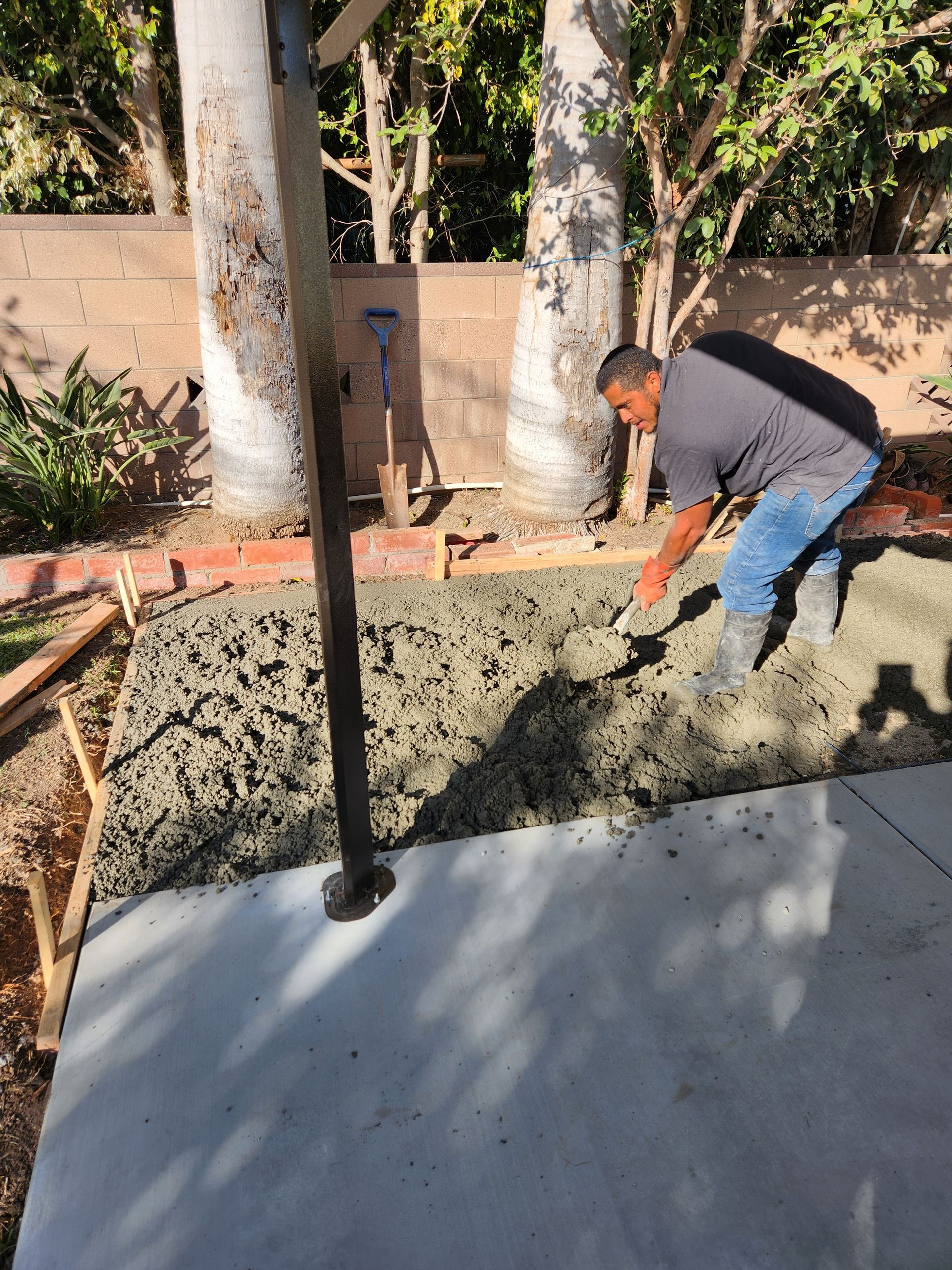 A man is pouring concrete into a concrete slab.
