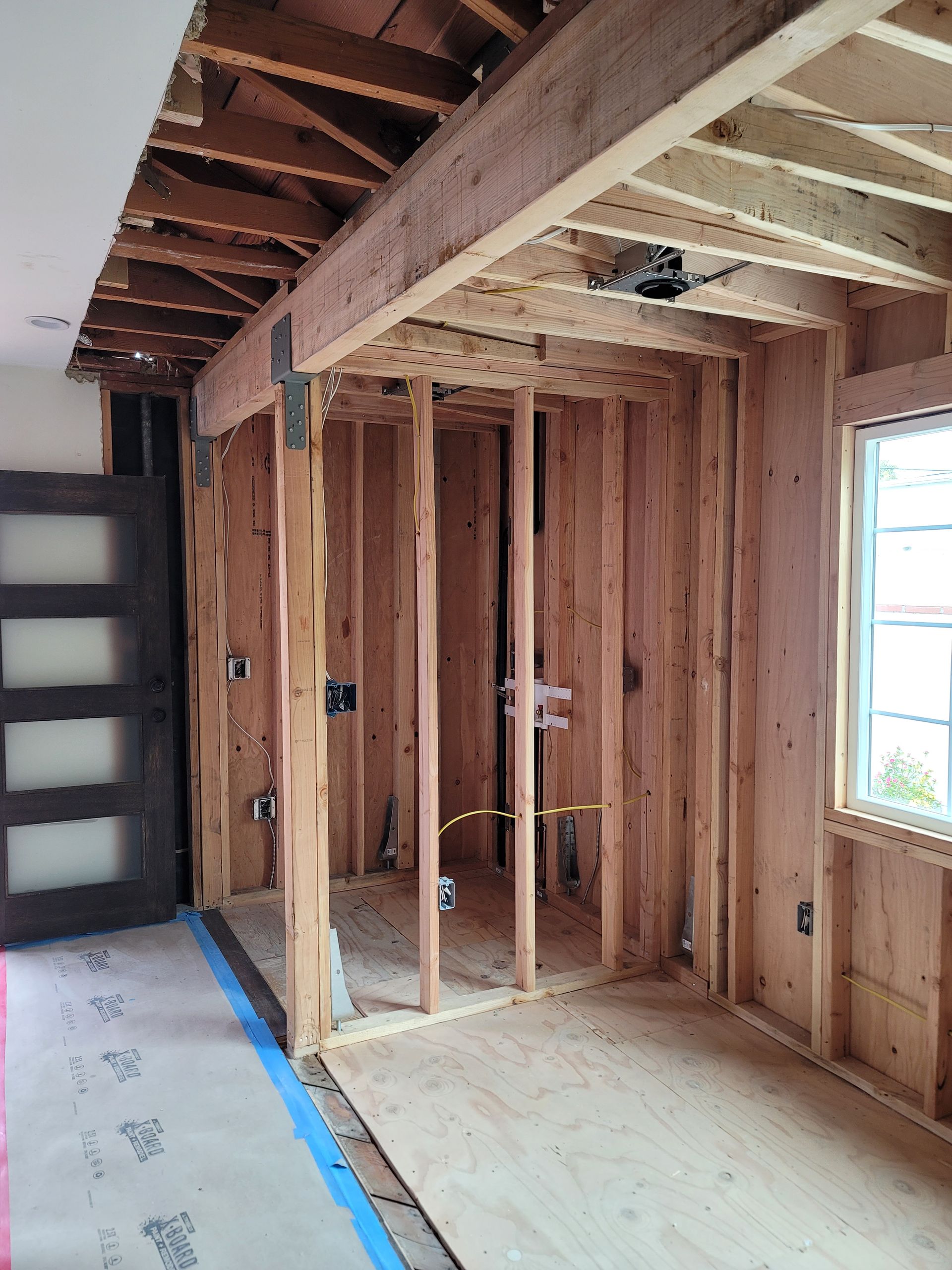 A room in a house under construction with wooden beams and a window.