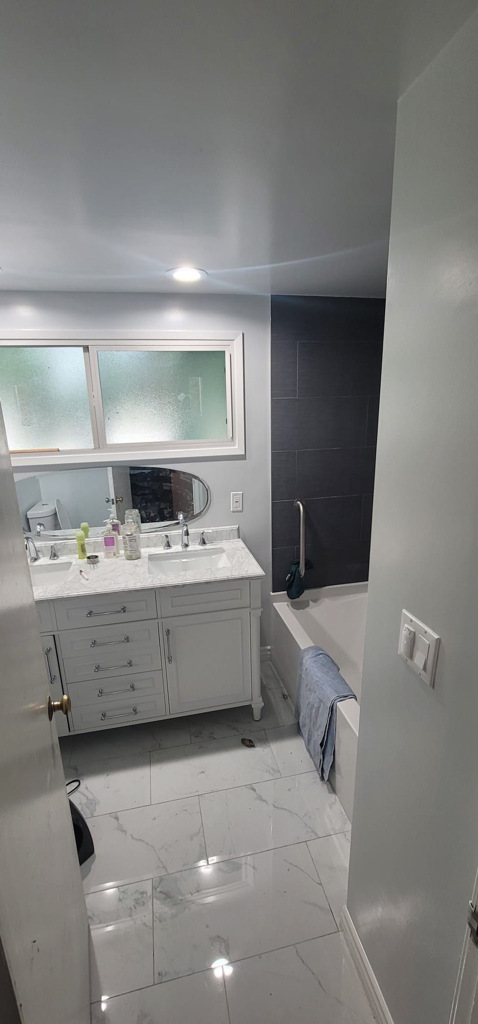 A bathroom with two sinks, a tub, and a window.