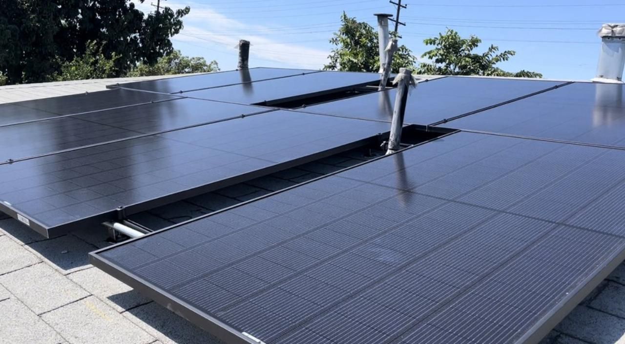 A row of solar panels are sitting on top of a roof.
