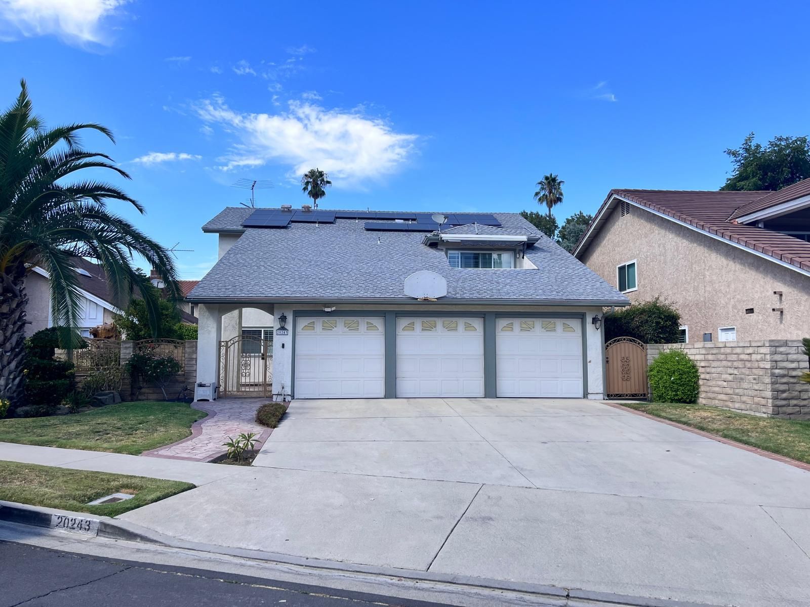A house with three garage doors and solar panels on the roof