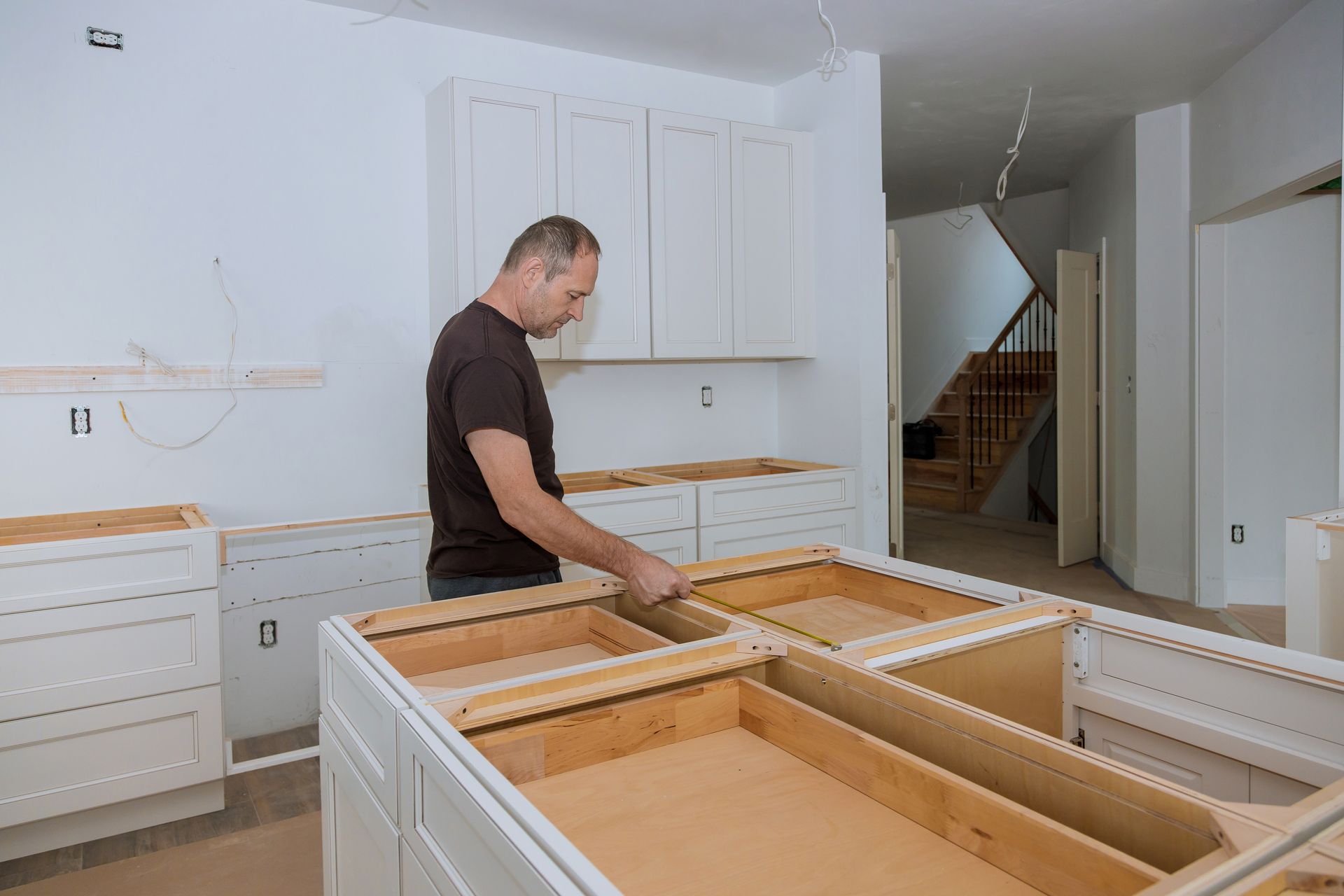 A man is installing cabinets in a kitchen.