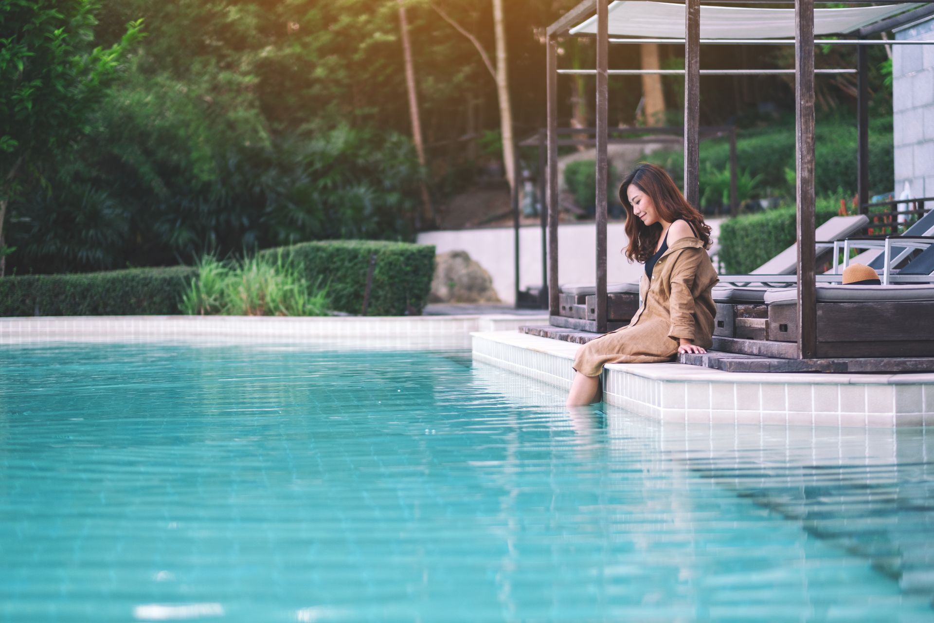 A woman is sitting on the edge of a swimming pool.