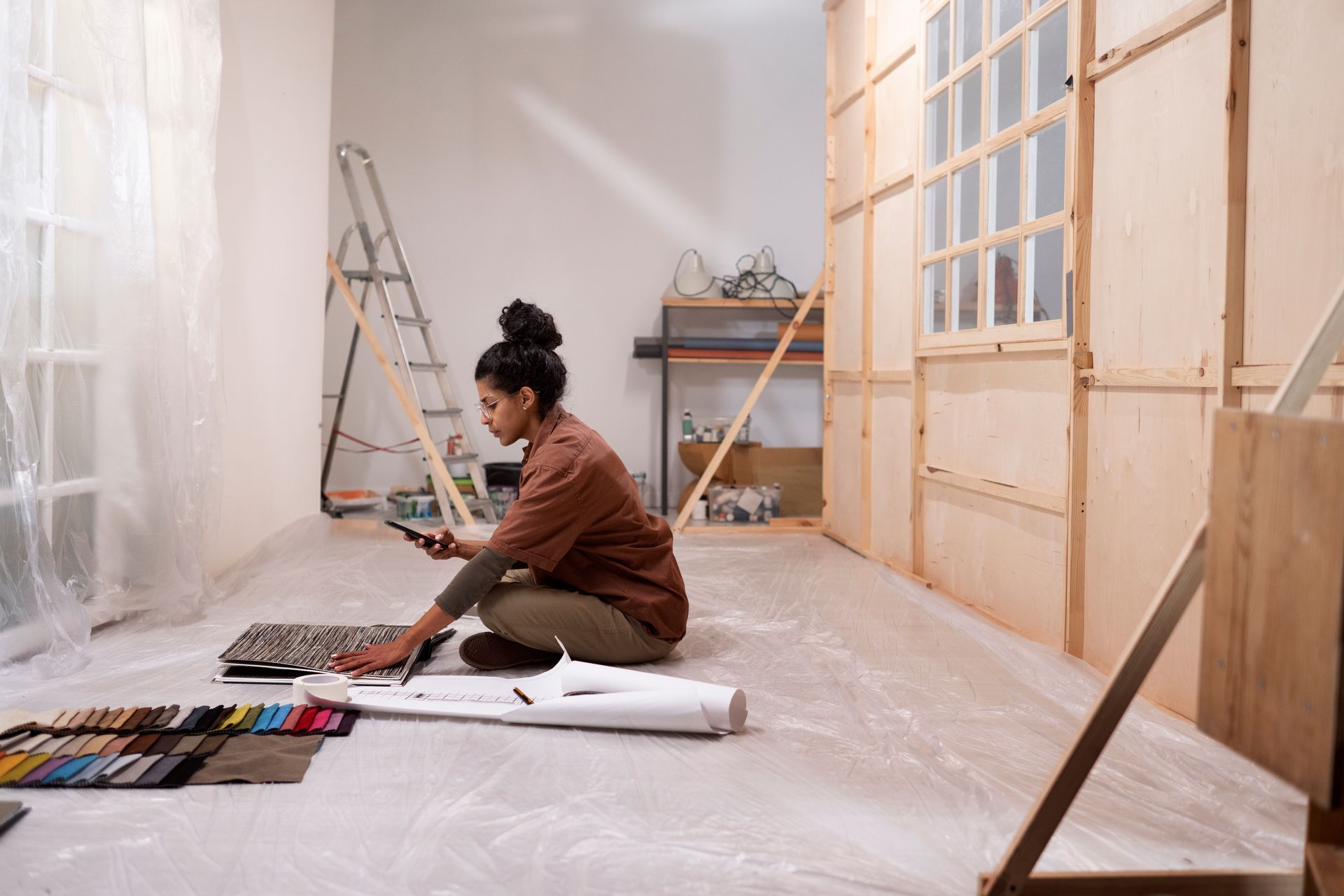 A woman is sitting on the floor in a room looking at a tablet.