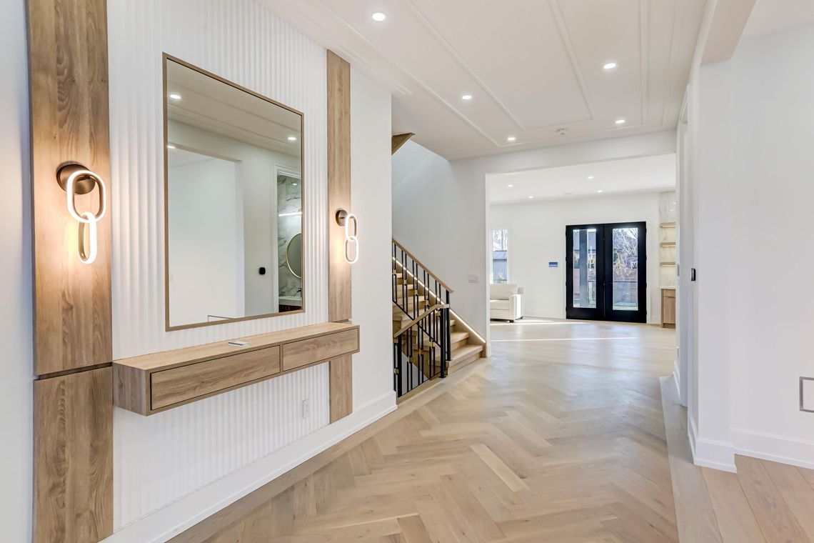 A hallway with a mirror and stairs in a house.