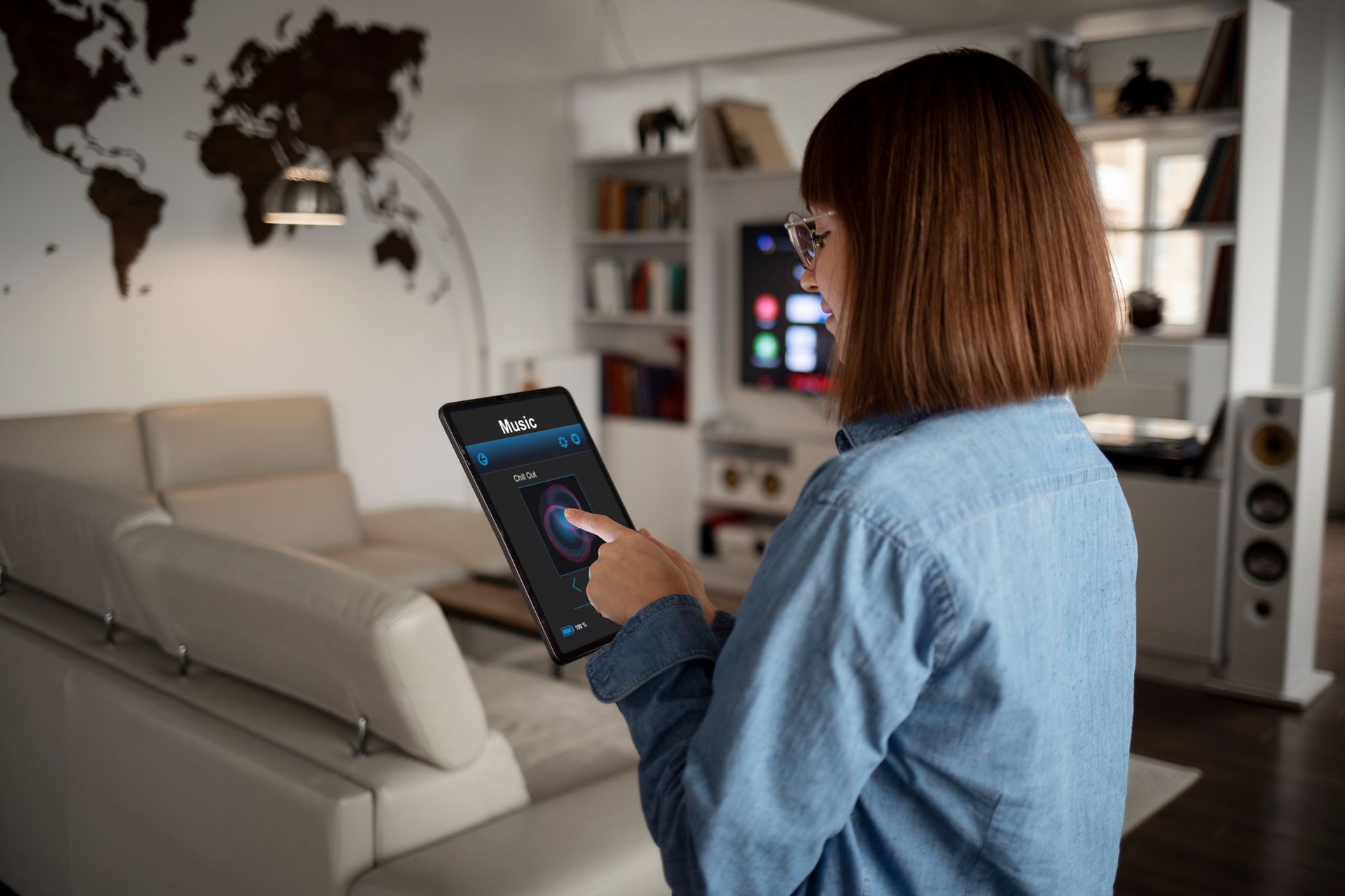 Woman using a wall-mounted tablet with interior view; wearing a red scarf; standing in a hallway.