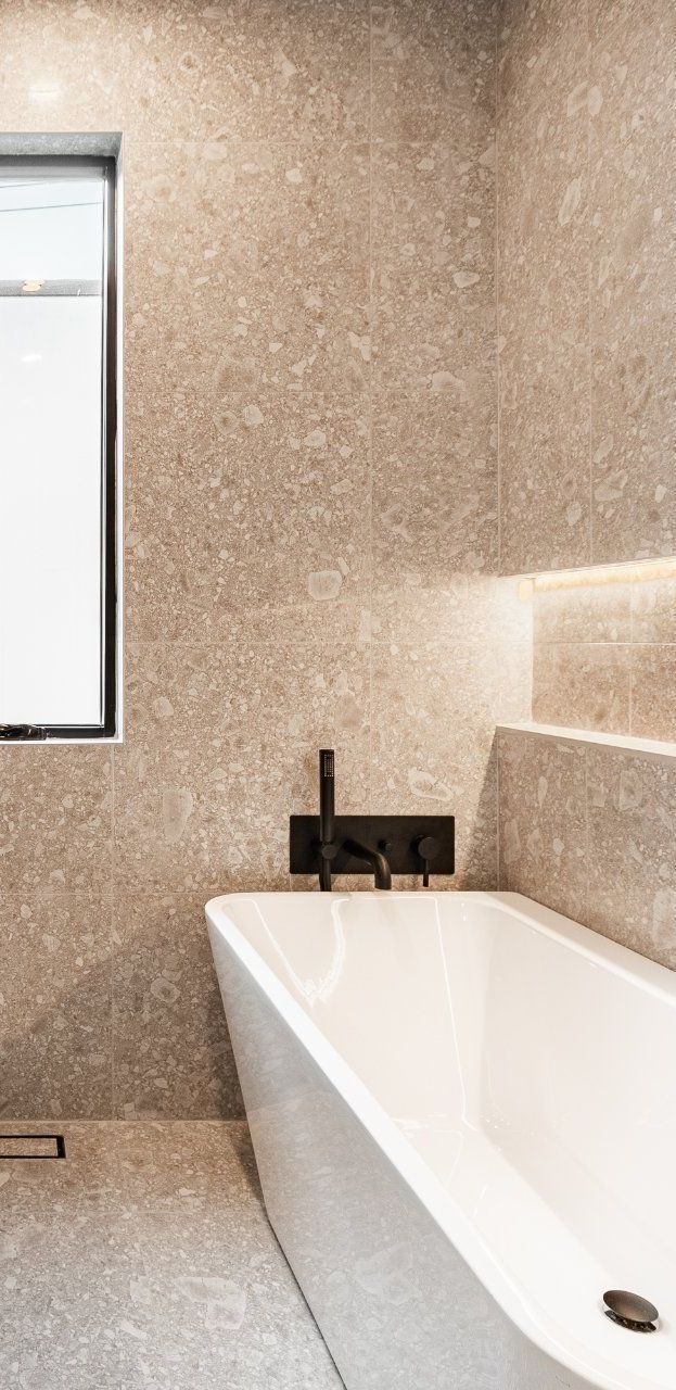 Une salle de bain avec baignoire , lavabo , miroirs et fenêtre.