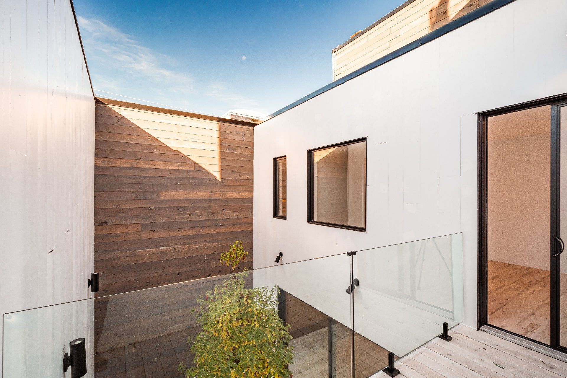 Une maison blanche avec un balcon et un arbre au milieu.