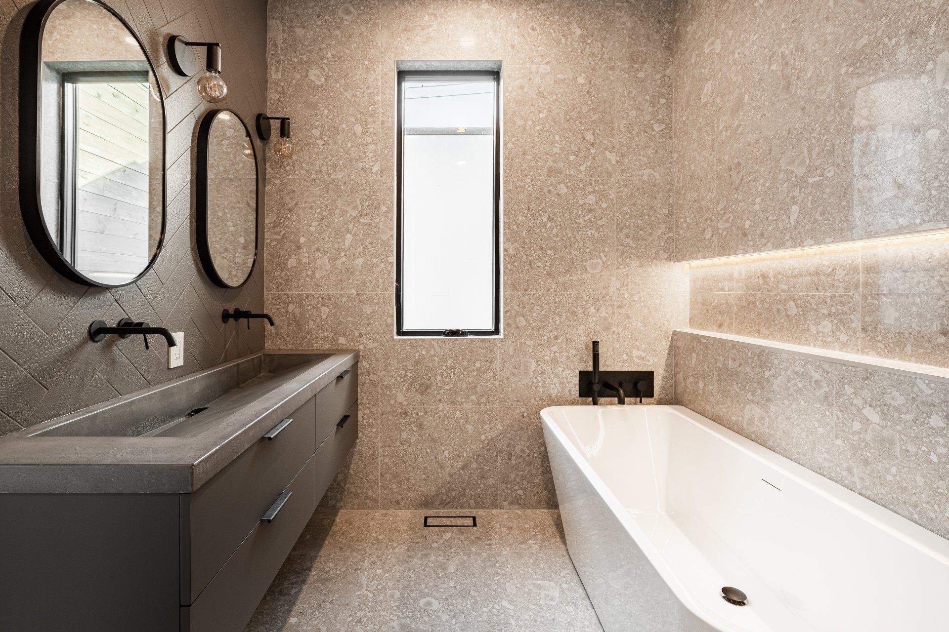 Une salle de bain avec baignoire , lavabo , miroirs et fenêtre.