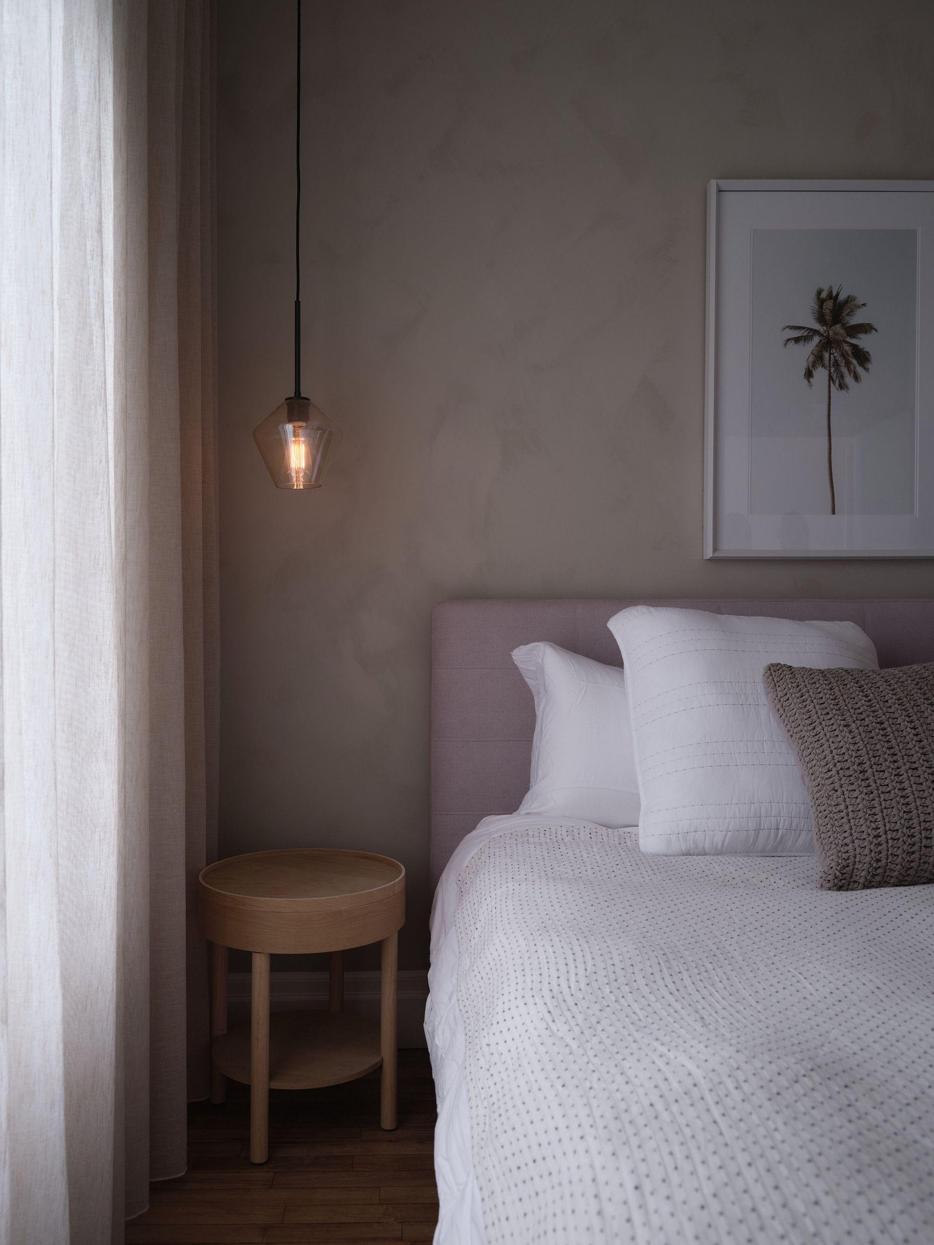 Il y a une photo d'un palmier sur le mur au dessus du lit.