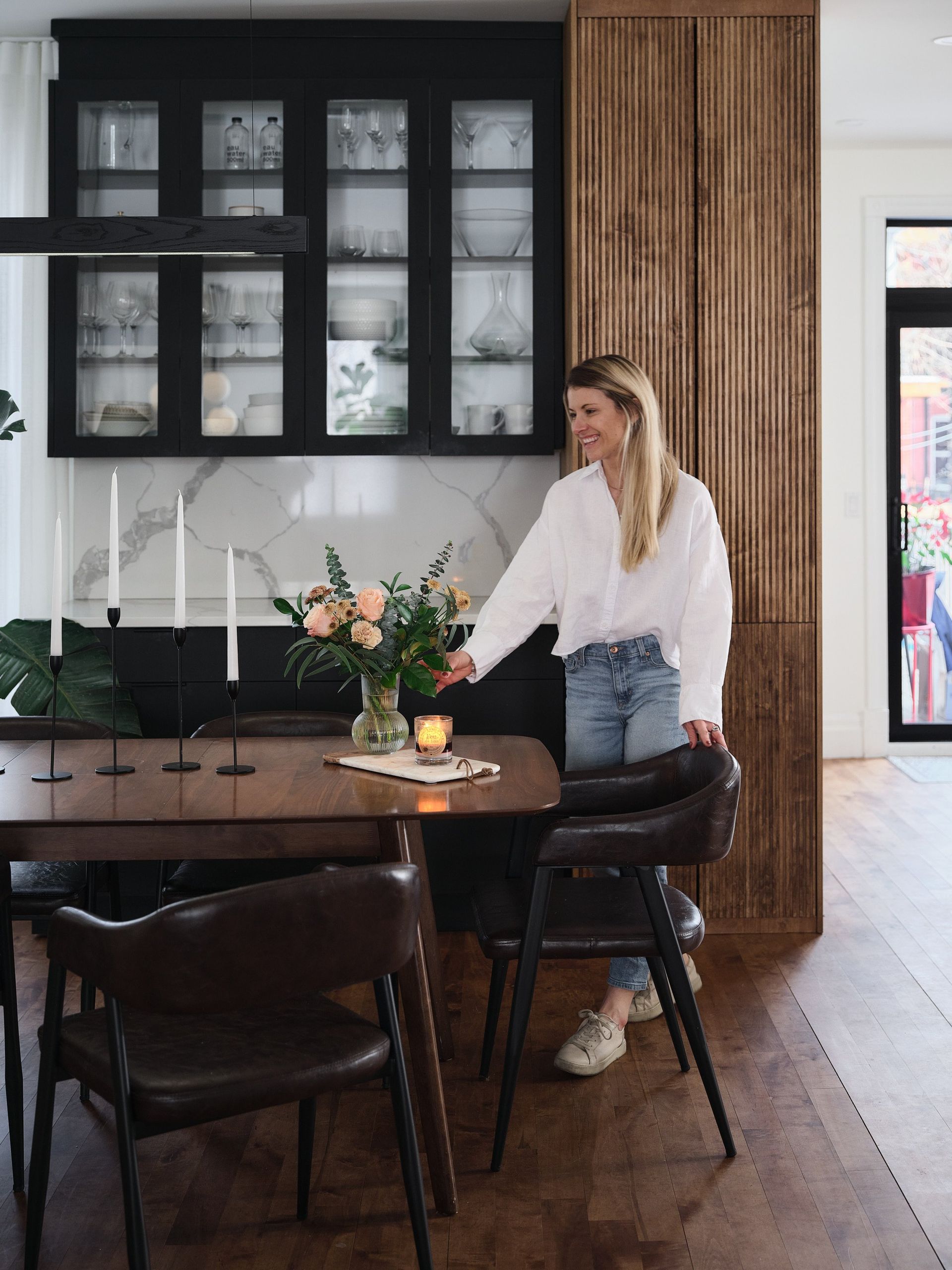 Une femme se tient à côté d'une table à manger dans une cuisine.