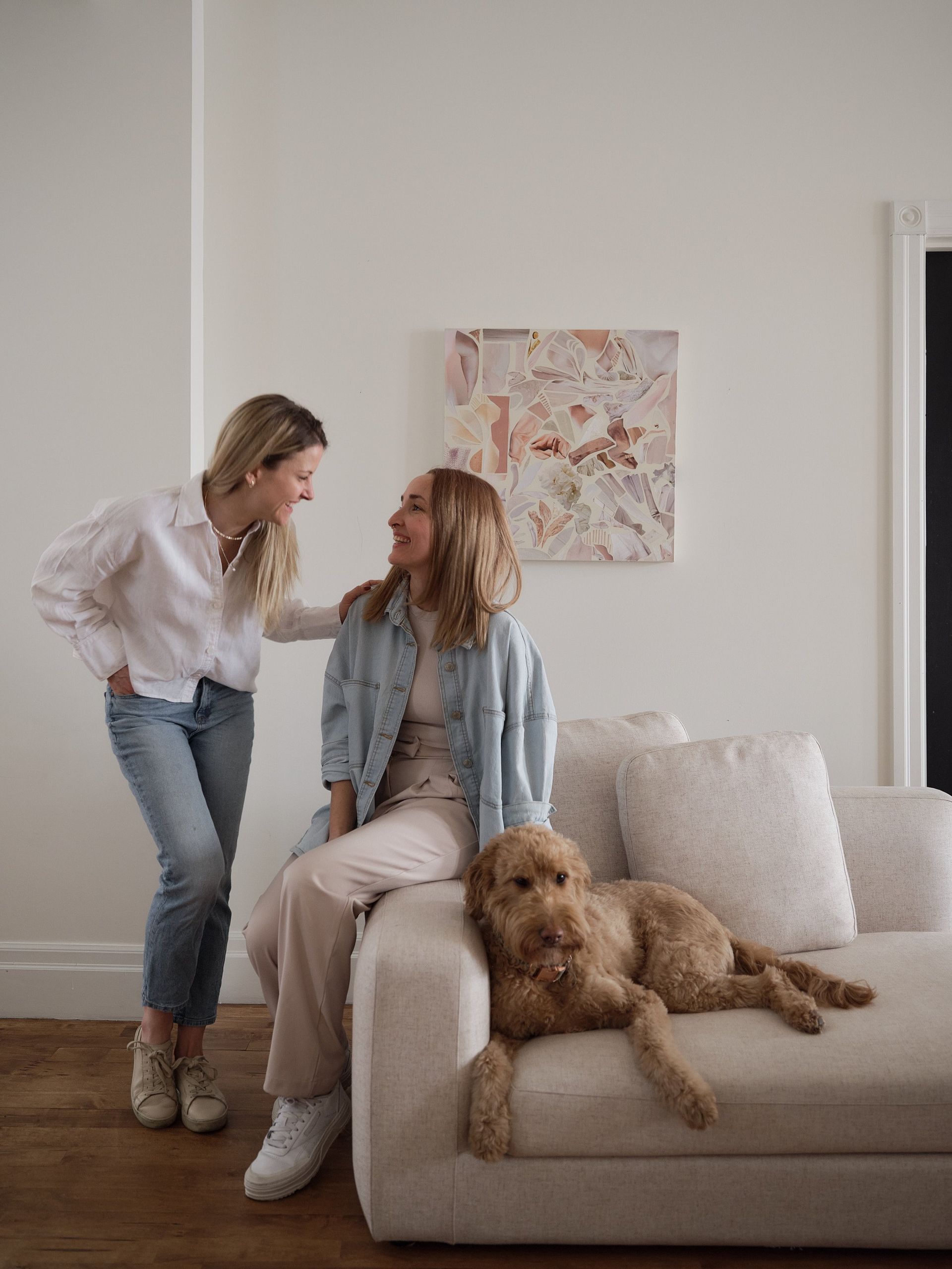 Deux femmes sont assises sur un canapé avec un chien.