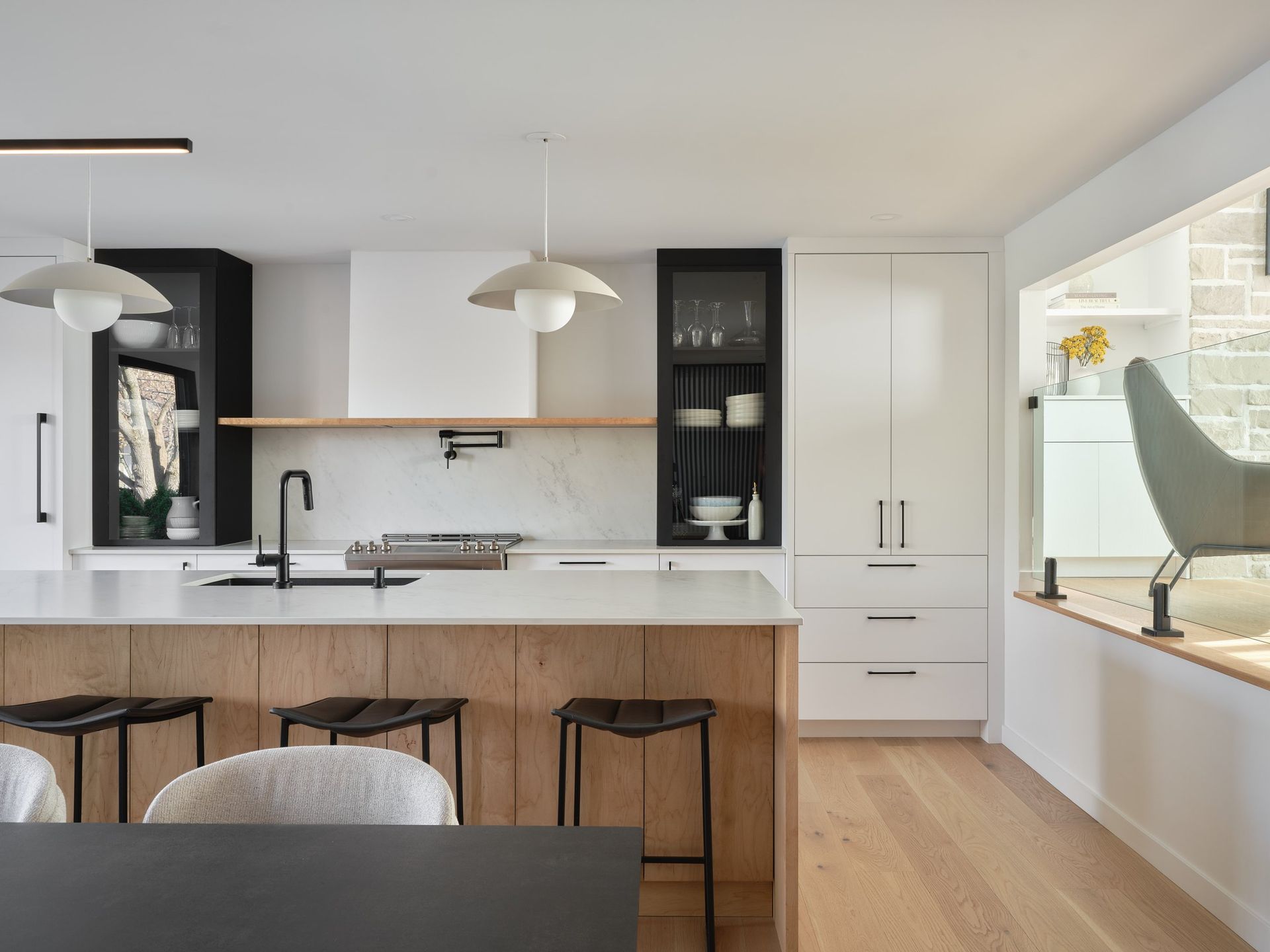 Une cuisine avec un grand îlot , des tabourets , une table et une chaise.