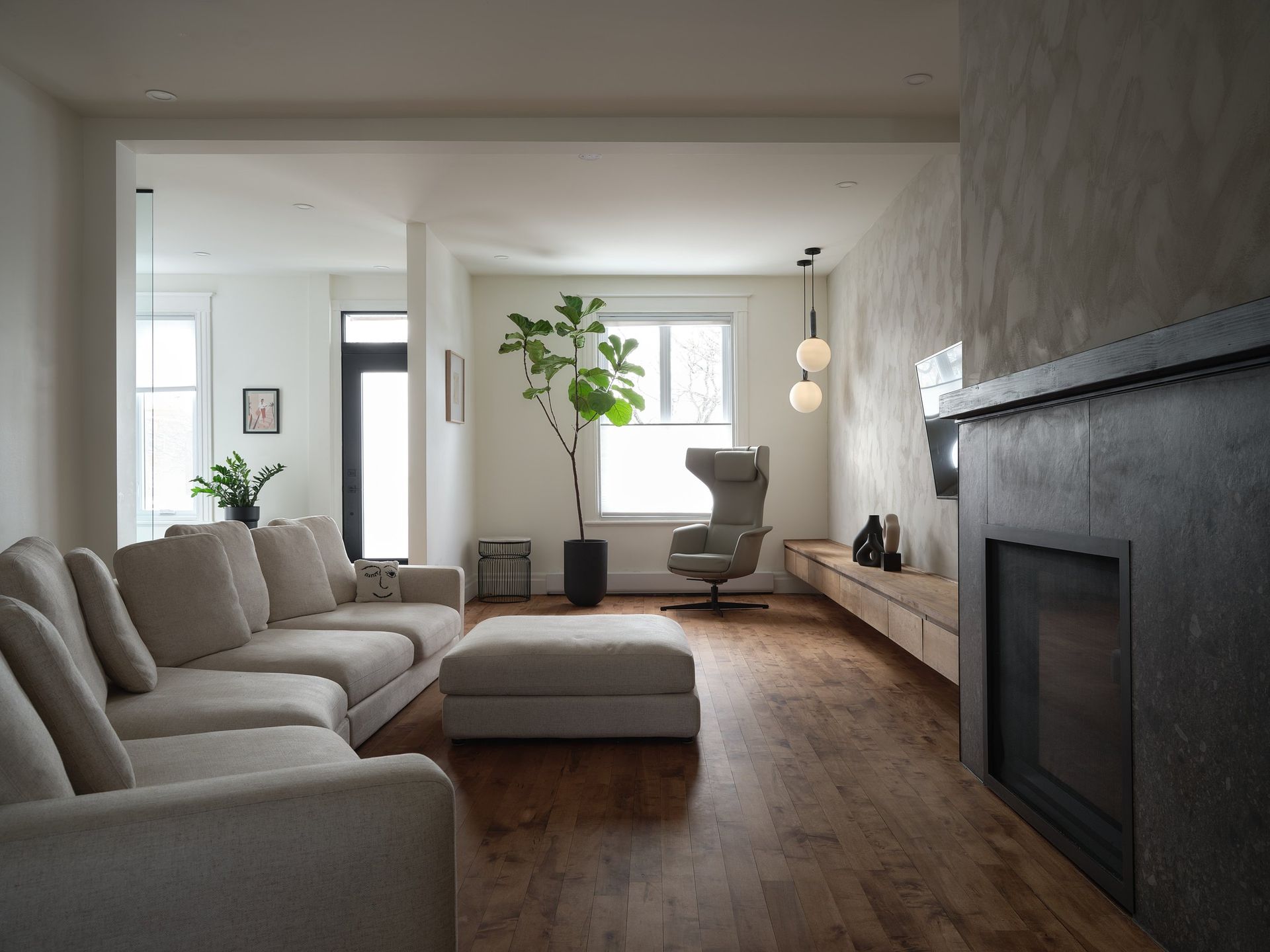 Un salon avec un canapé, un fauteuil, un pouf et une cheminée.