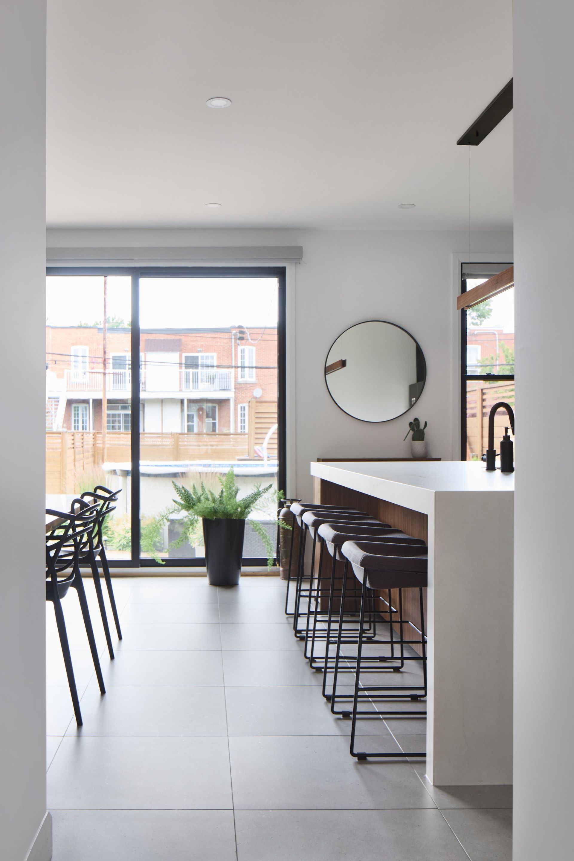 Une cuisine avec tabourets , un comptoir , un miroir et une porte coulissante vitrée.