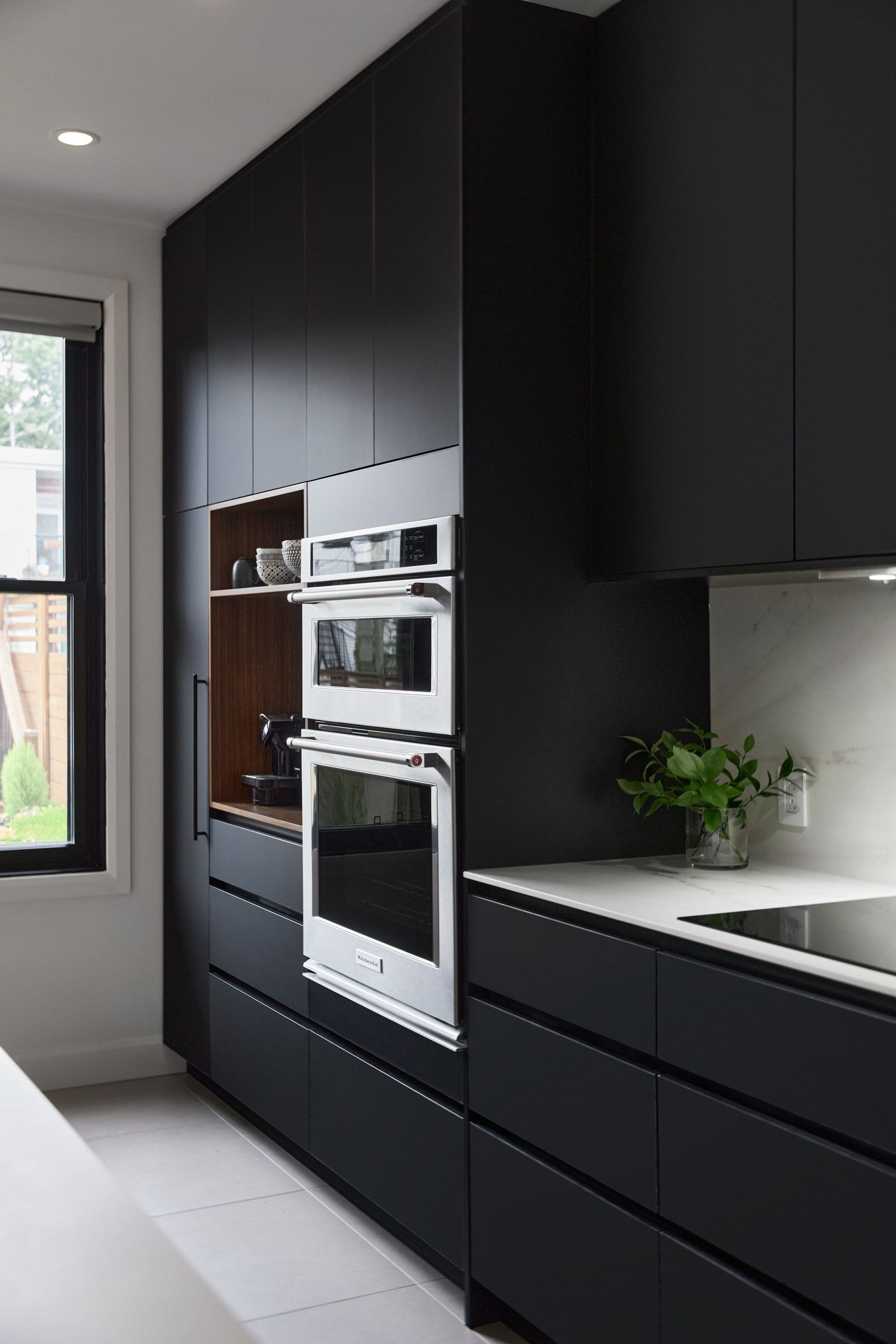 Une cuisine avec armoires noires et appareils électroménagers en acier inoxydable.