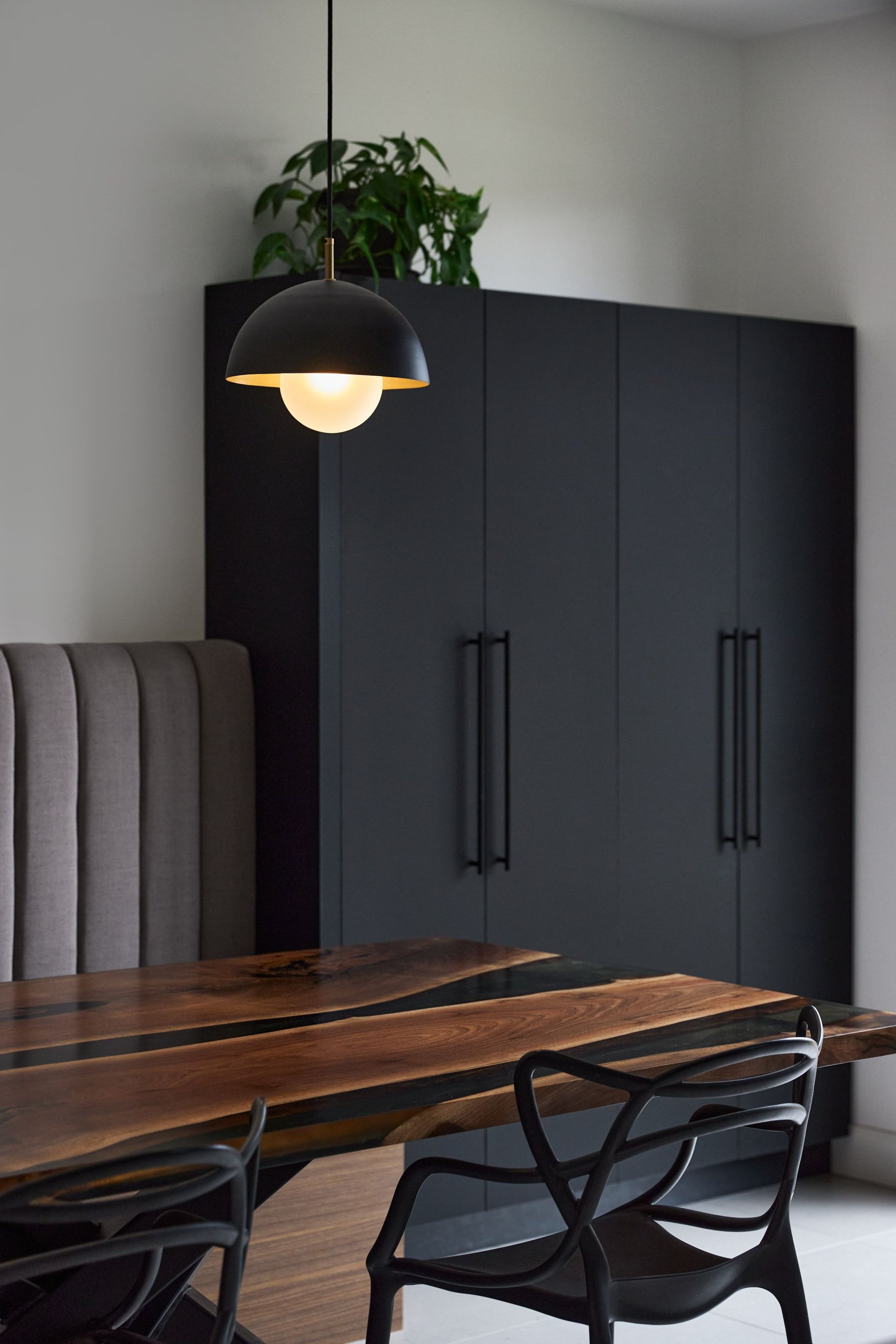Une salle à manger avec une table et des chaises en bois et un meuble noir.