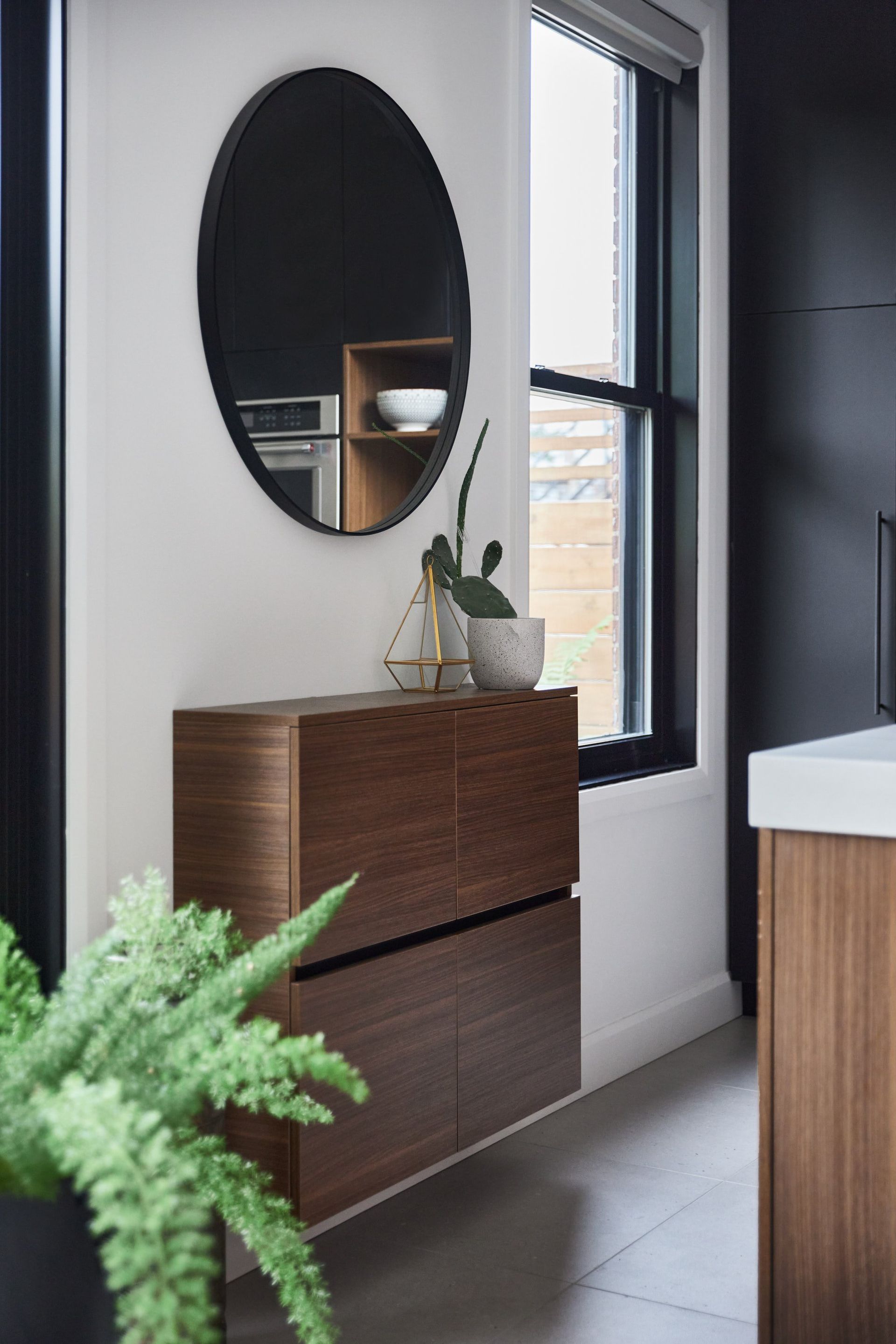 Un miroir rond est accroché au mur au-dessus d'une armoire en bois.