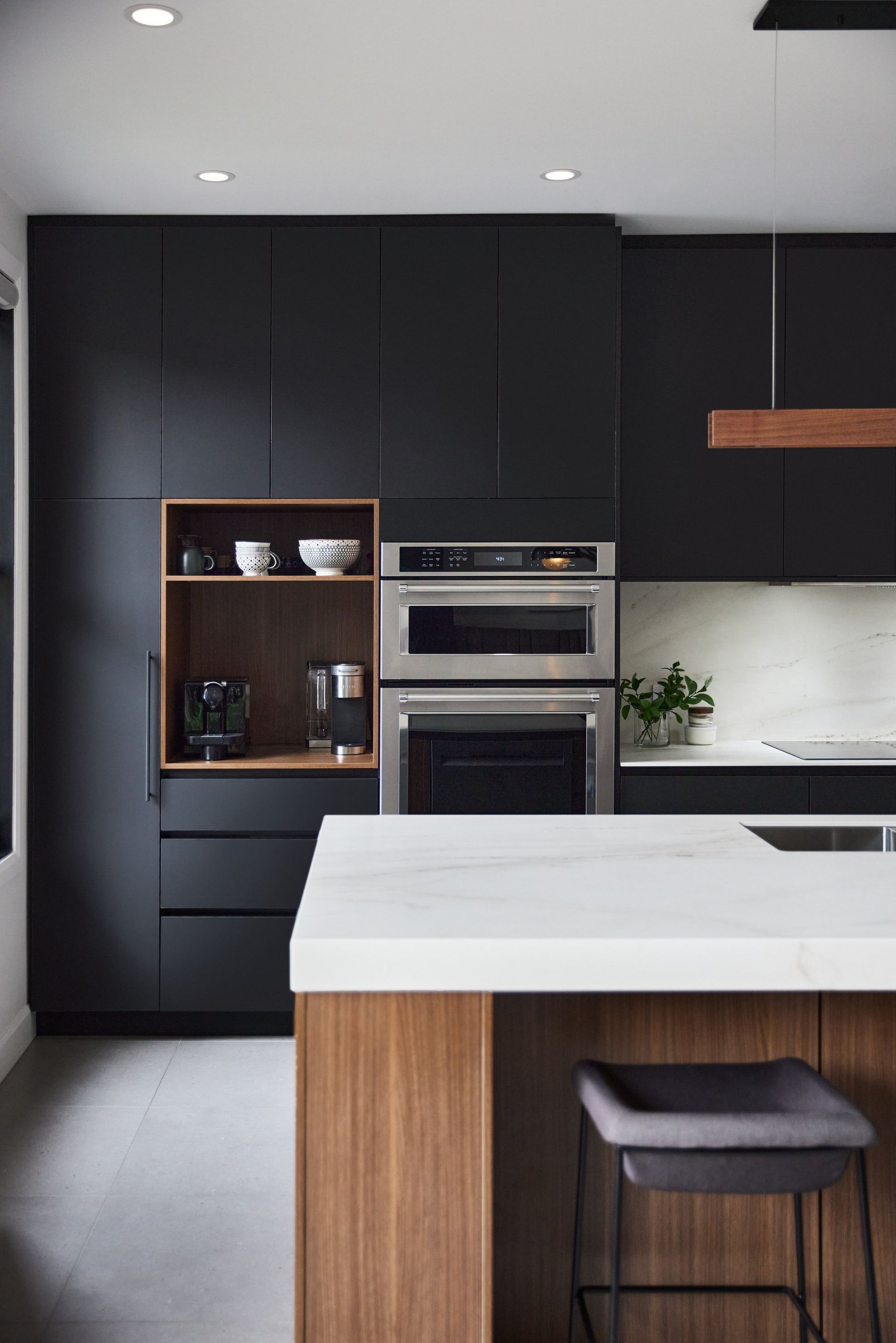 Une cuisine avec des armoires noires et un comptoir blanc