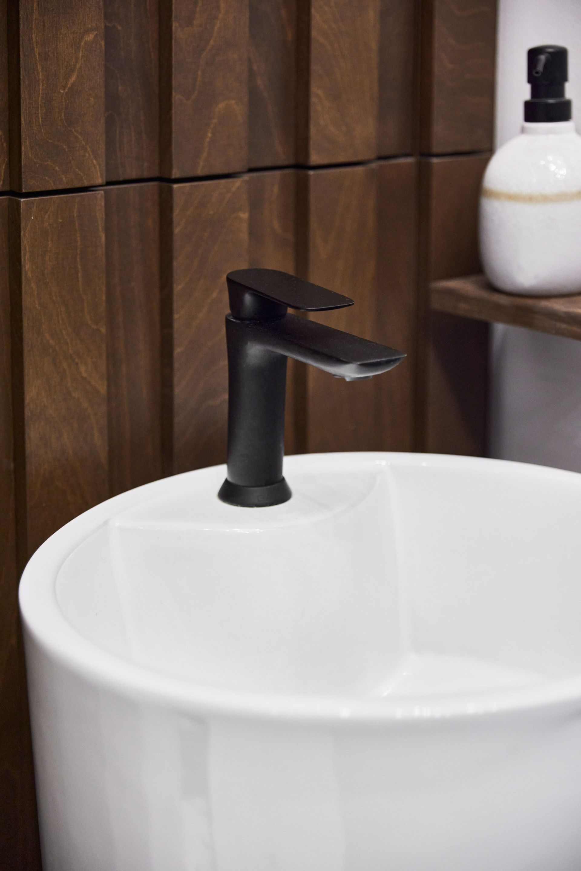 Un lavabo blanc avec un robinet noir dans une salle de bain.